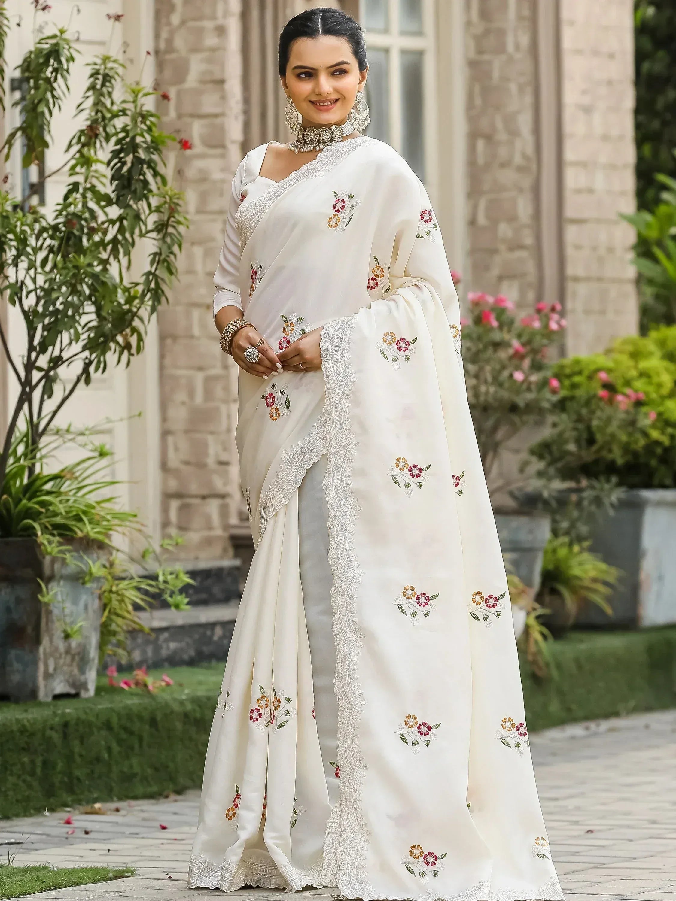 White embroidered saree with floral motifs and lace border, styled with traditional jewelry for ethnic occasions