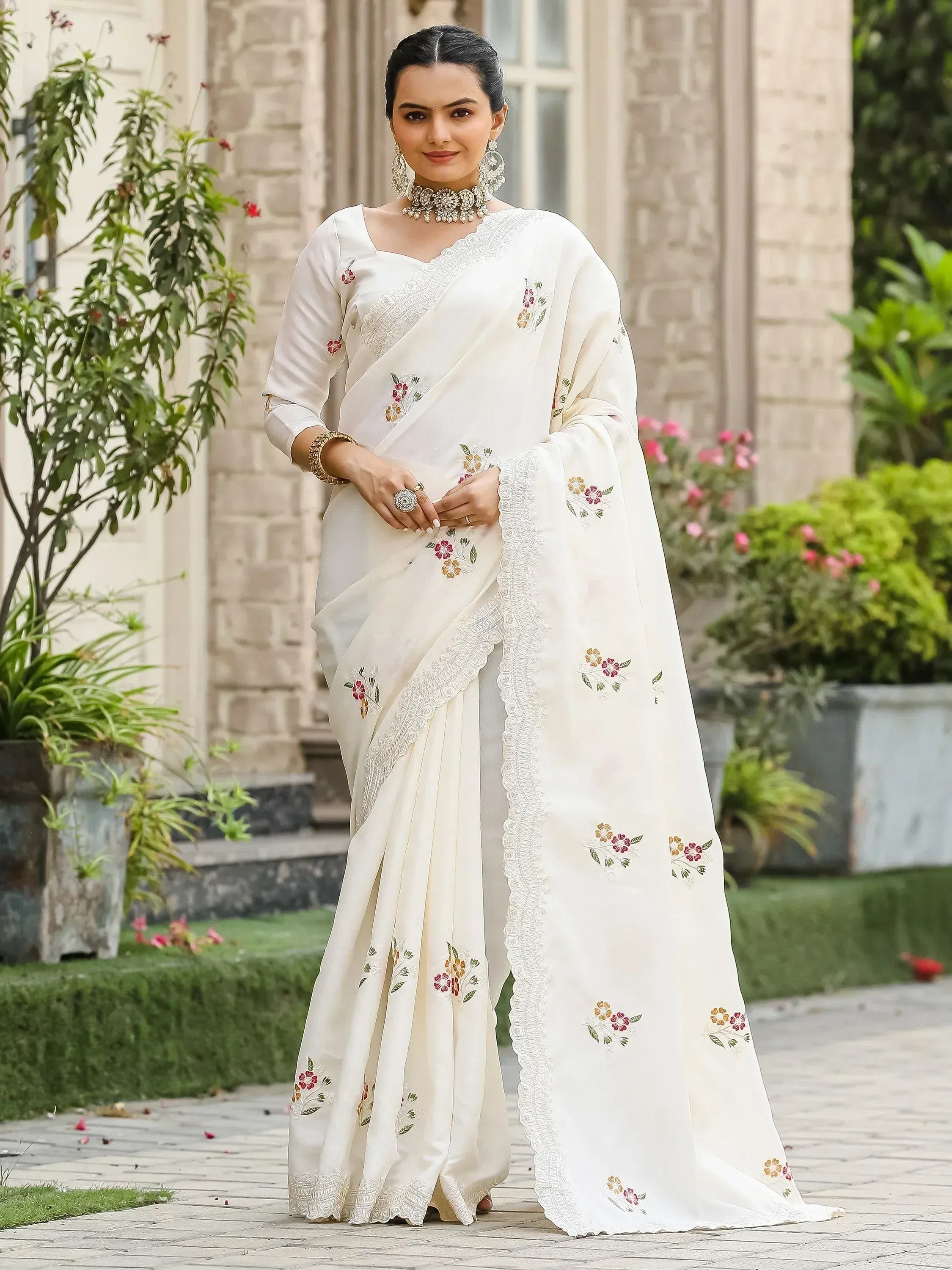 White embroidered saree with floral motifs and lace border, styled with traditional jewelry for ethnic wear