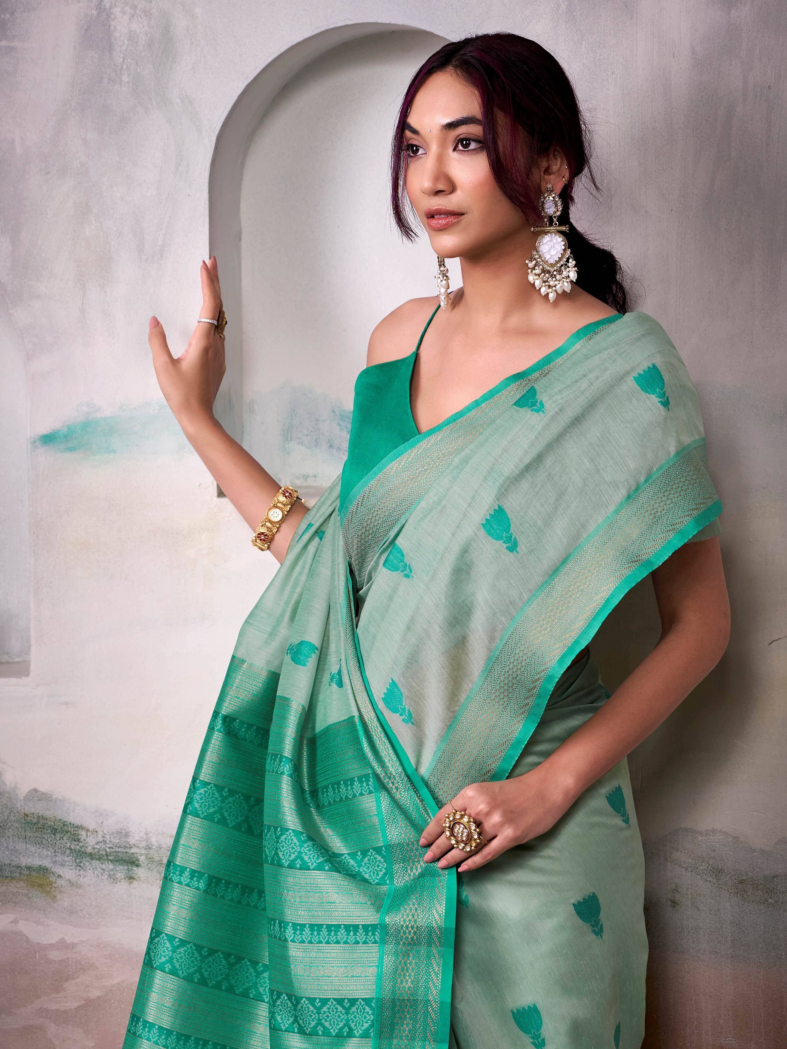 Mint green saree with floral motifs and gold border, paired with green blouse and traditional jewelry