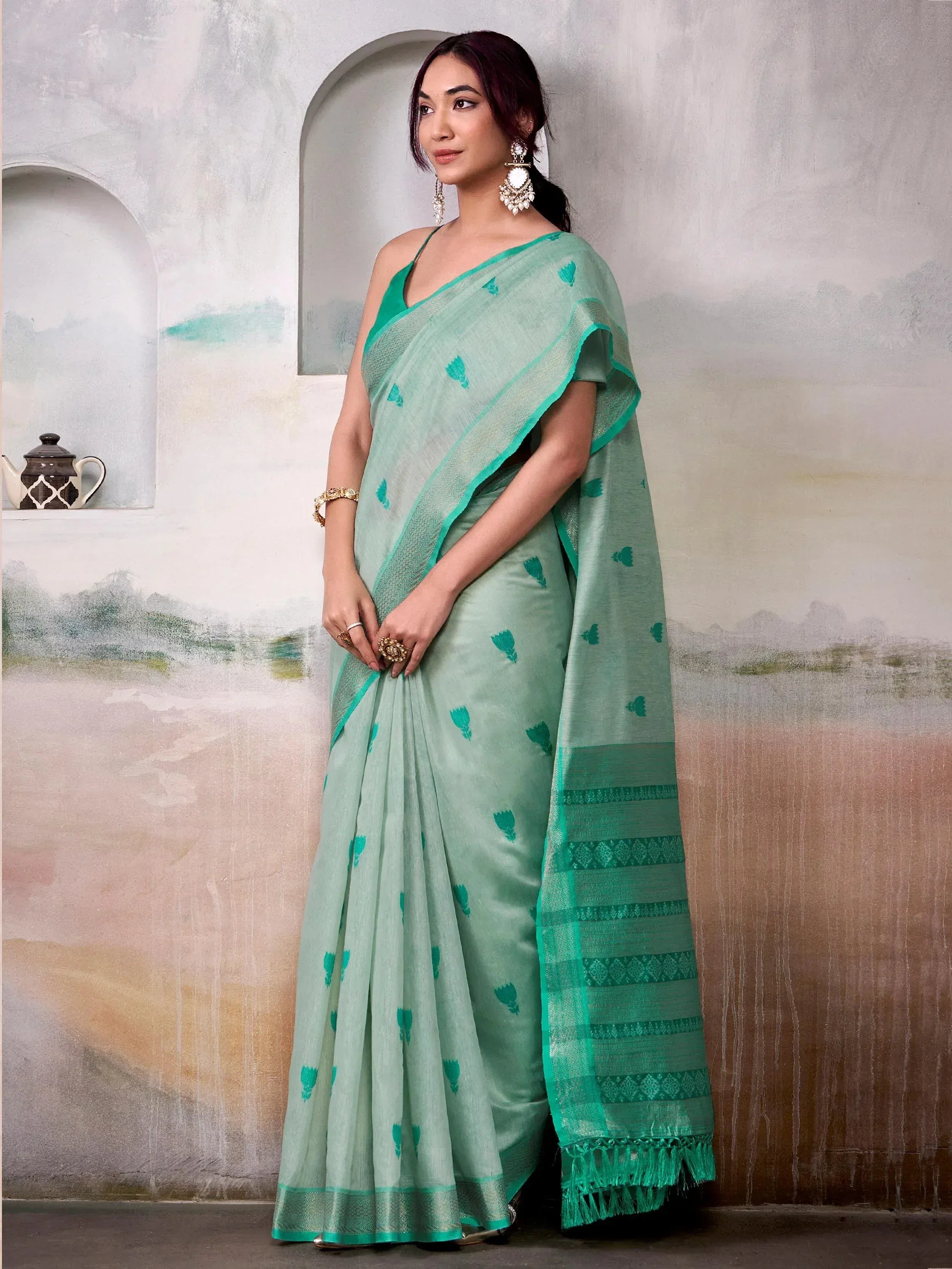 Mint green saree with leaf print and embroidered border, styled with statement earrings for ethnic wear