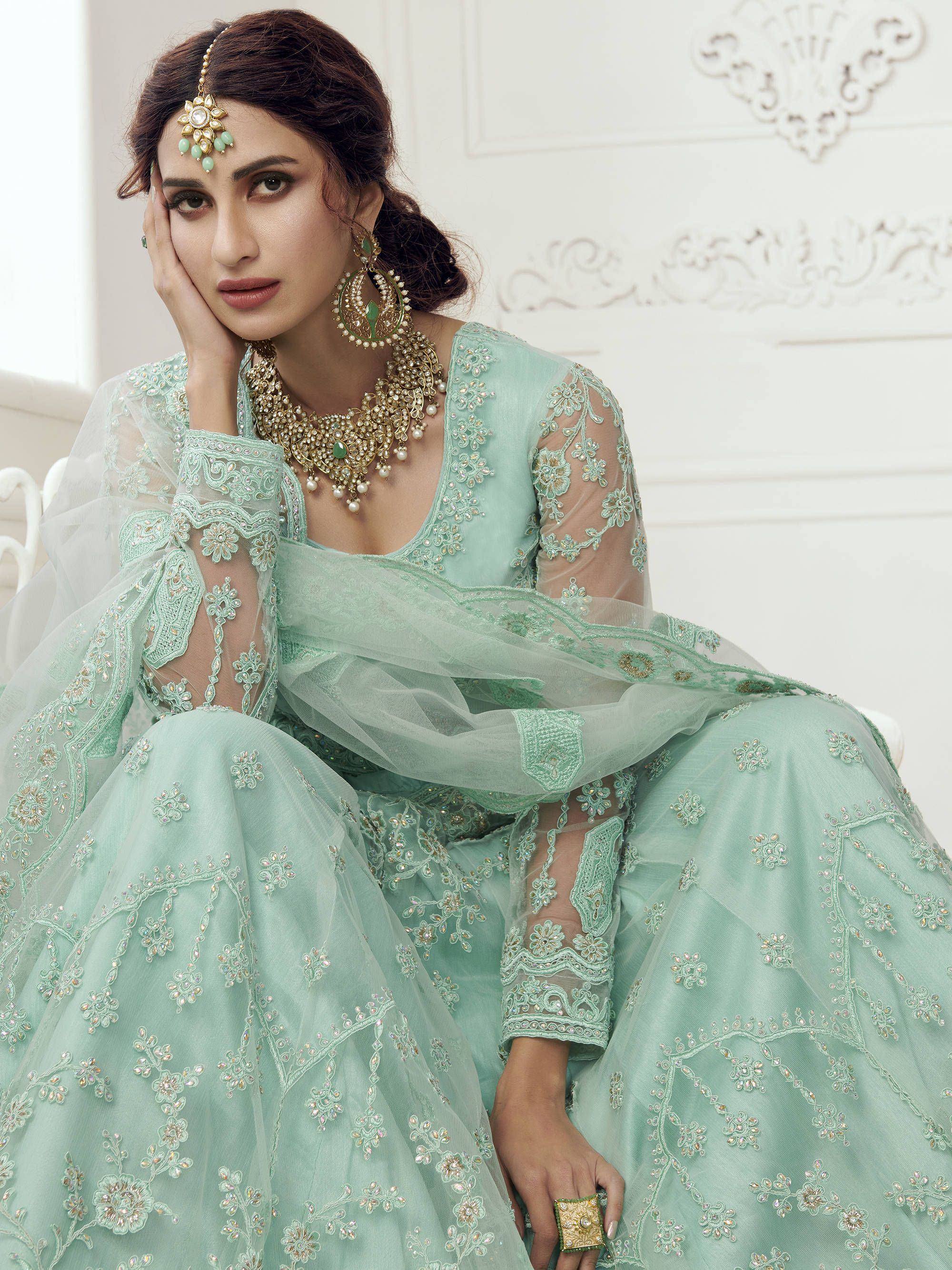 Mint green embroidered lehenga choli with sheer sleeves and gold jewelry, perfect for Indian ethnic occasions.