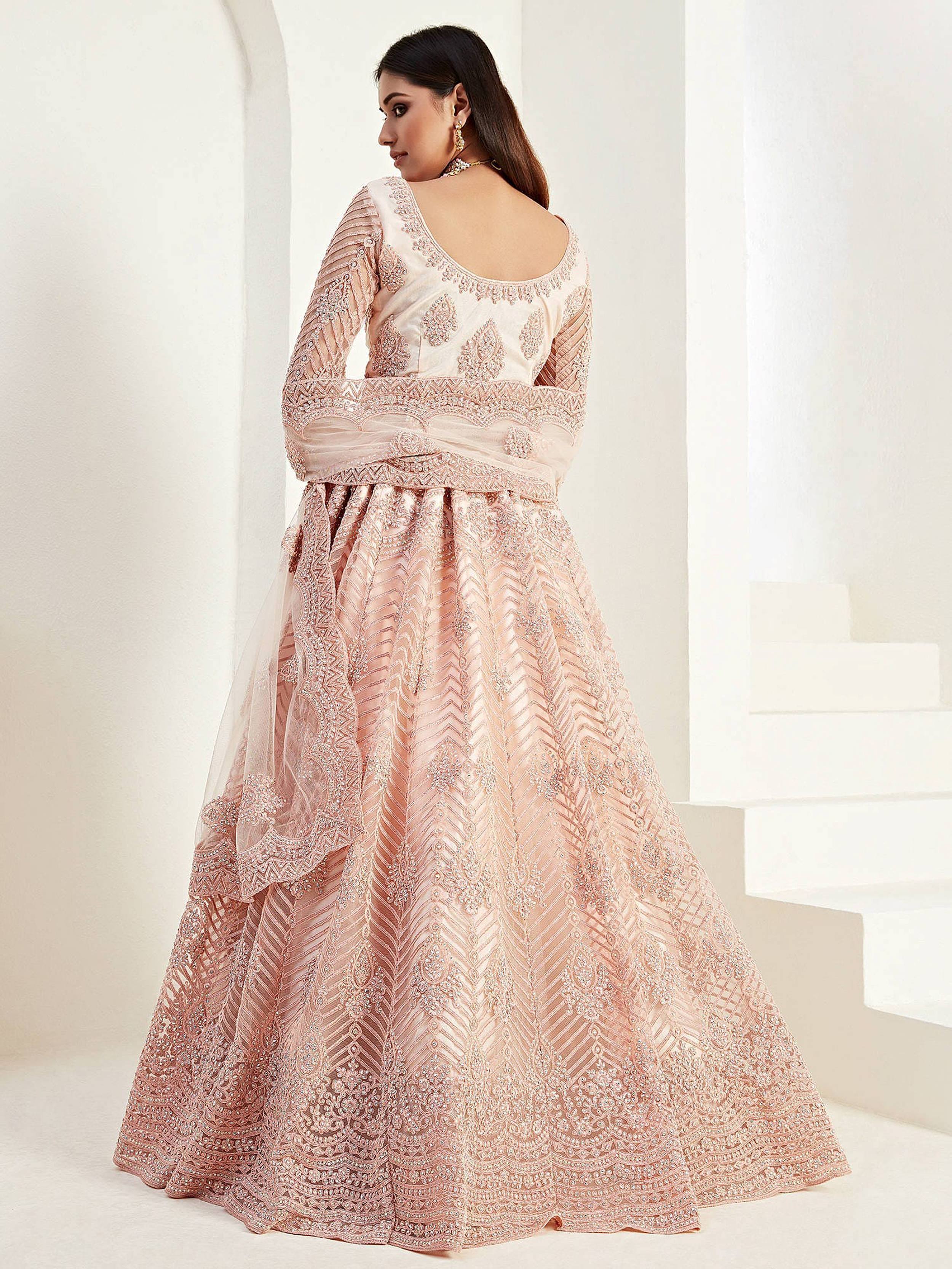 Elegant blush pink designer lehenga choli with intricate embroidery and sheer sleeves, perfect for weddings.