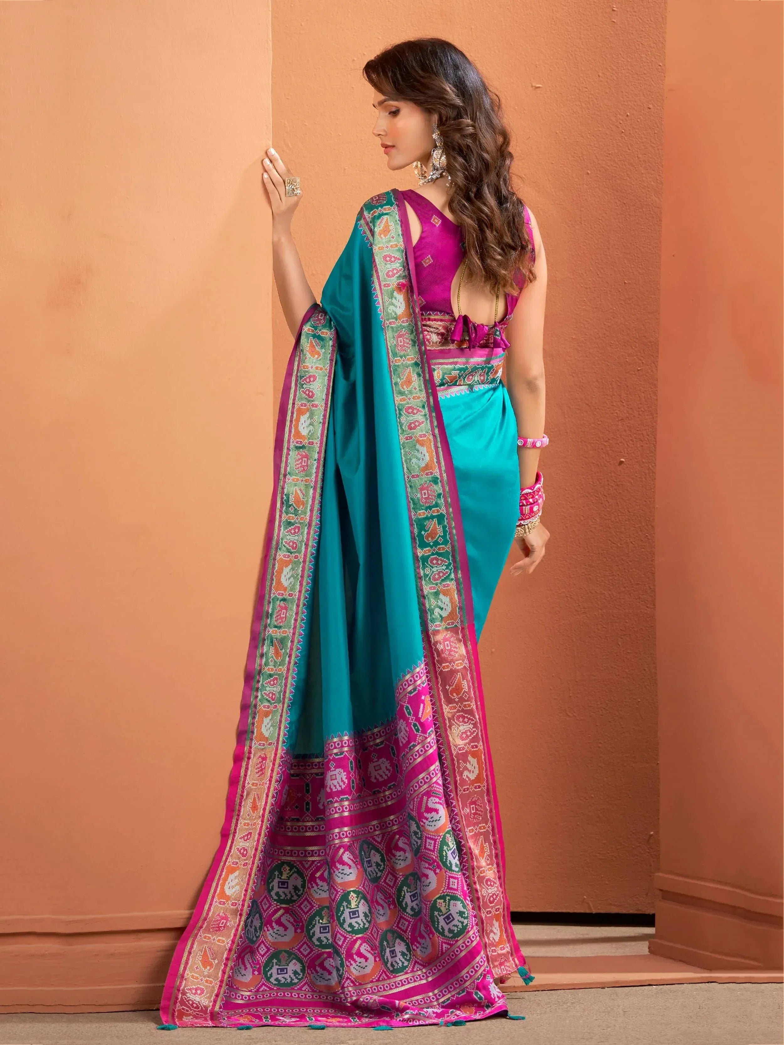 Teal and pink designer saree with intricate elephant print border, perfect for Indian ethnic wear occasions.