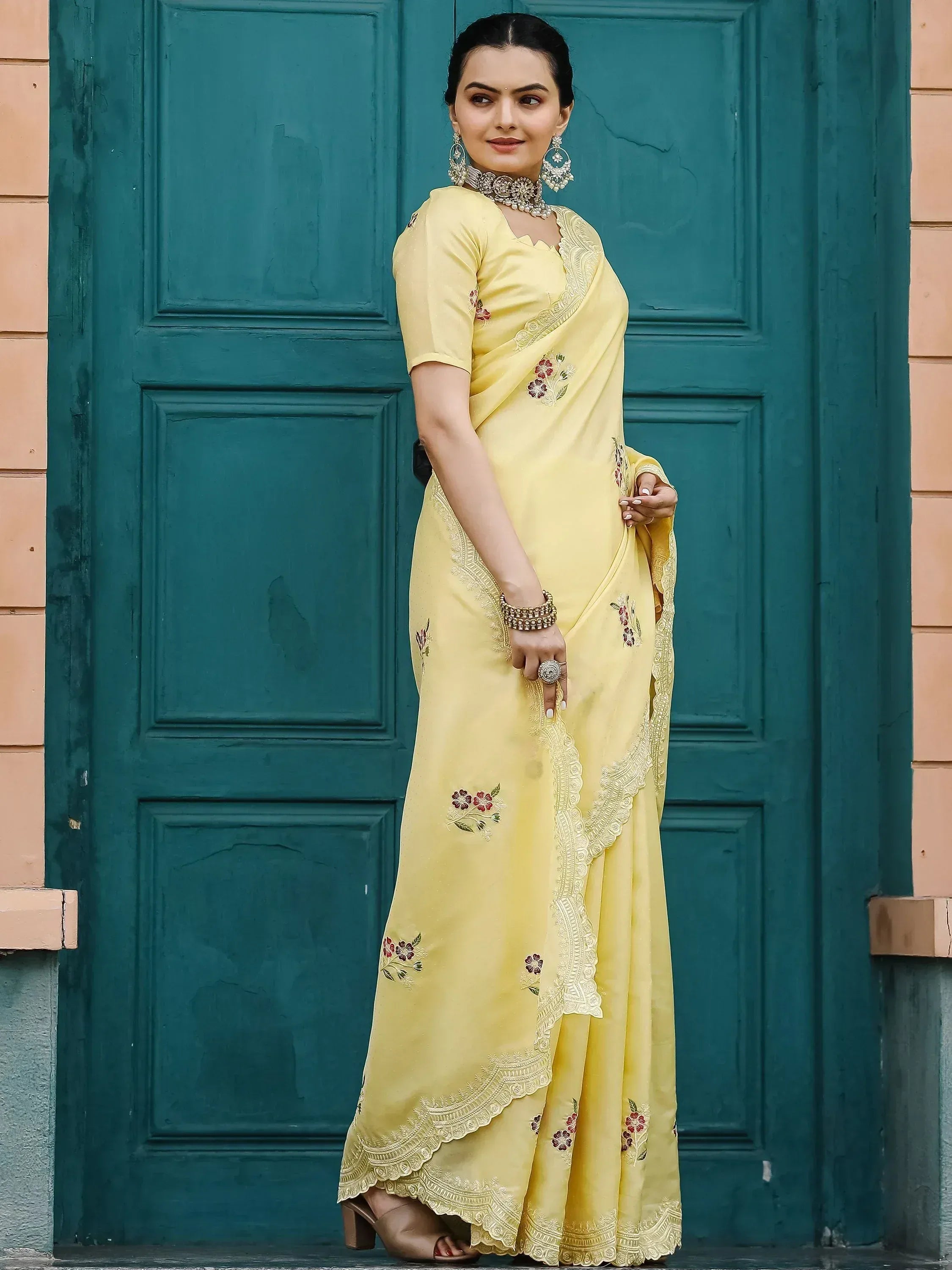 Yellow embroidered saree with floral details and lace border, styled with traditional jewelry