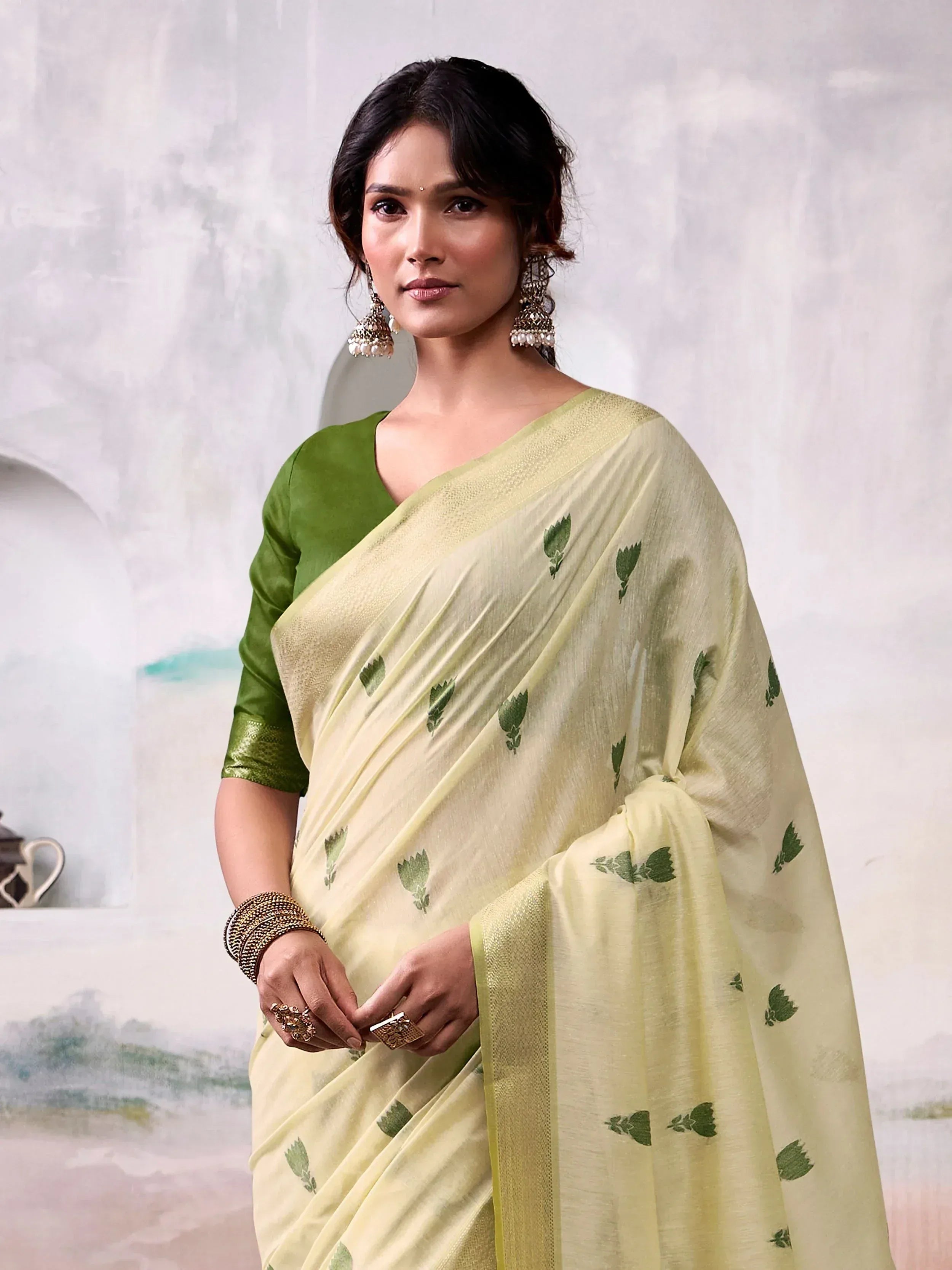 Elegant light yellow saree with green leaf prints, paired with a green blouse, perfect for ethnic occasions.