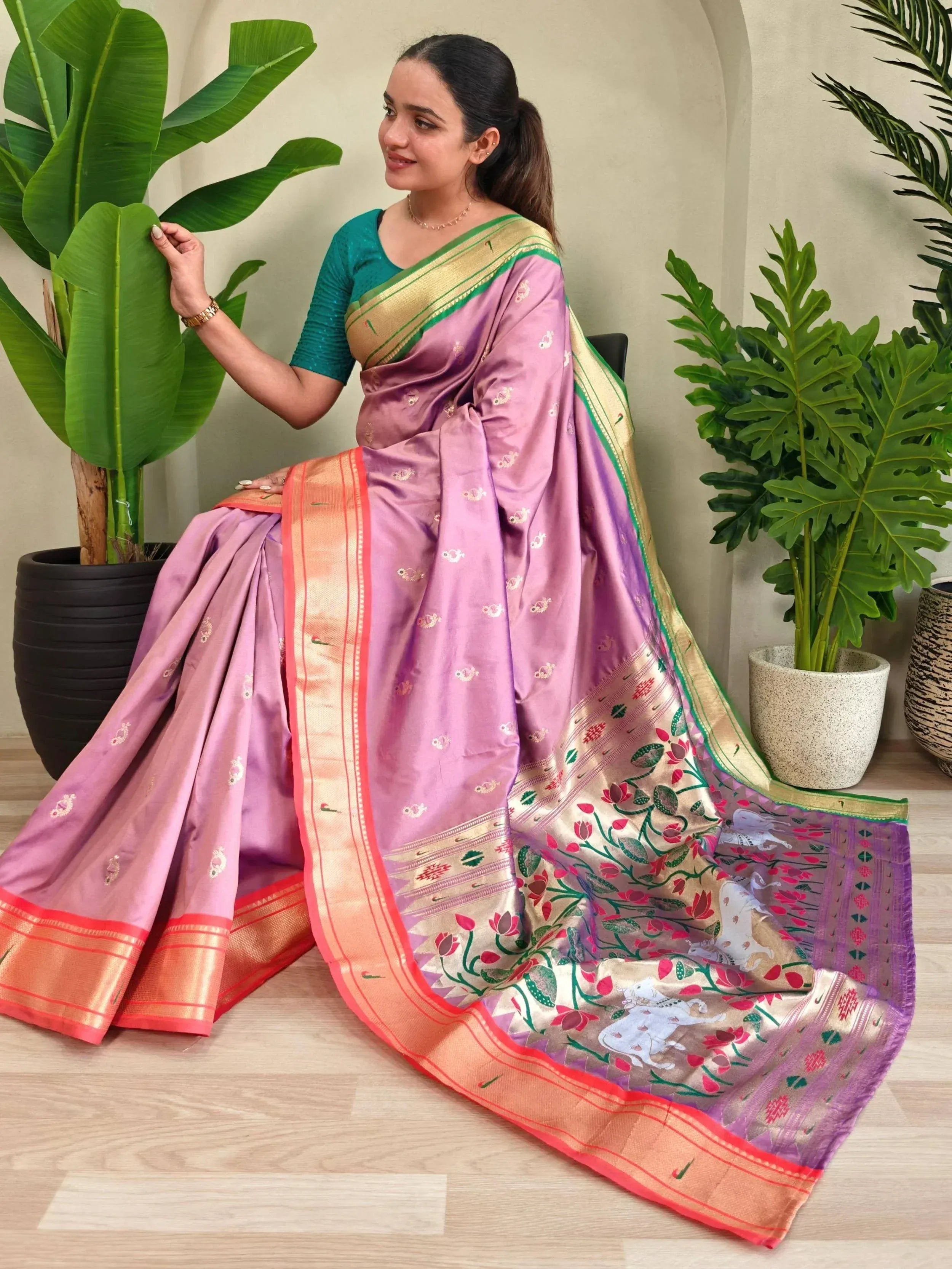 Woman in elegant purple silk saree with floral and elephant motifs, gold border, paired with teal blouse