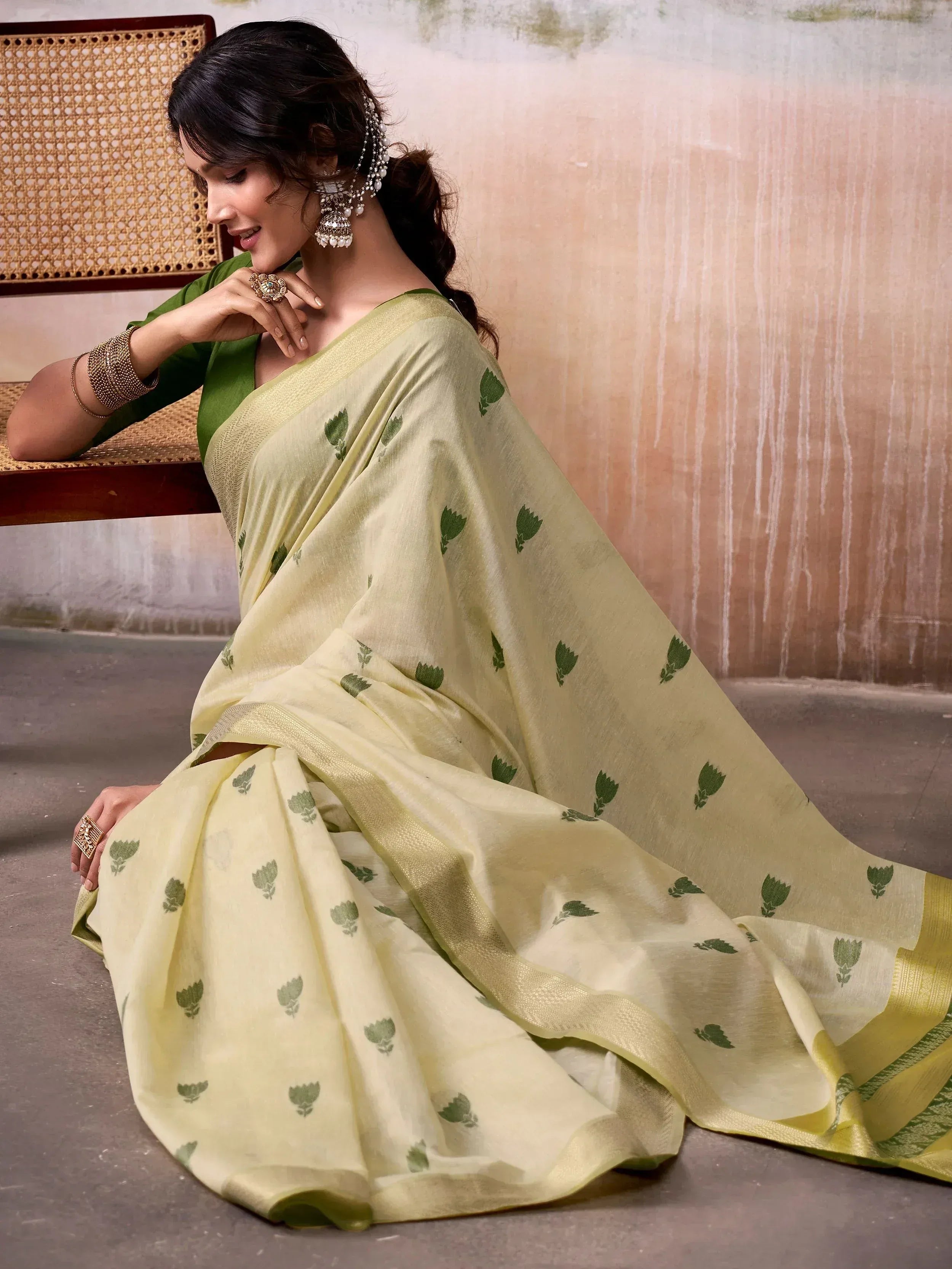 Woman in elegant light green saree with green leaf print, paired with matching blouse and traditional jewelry.