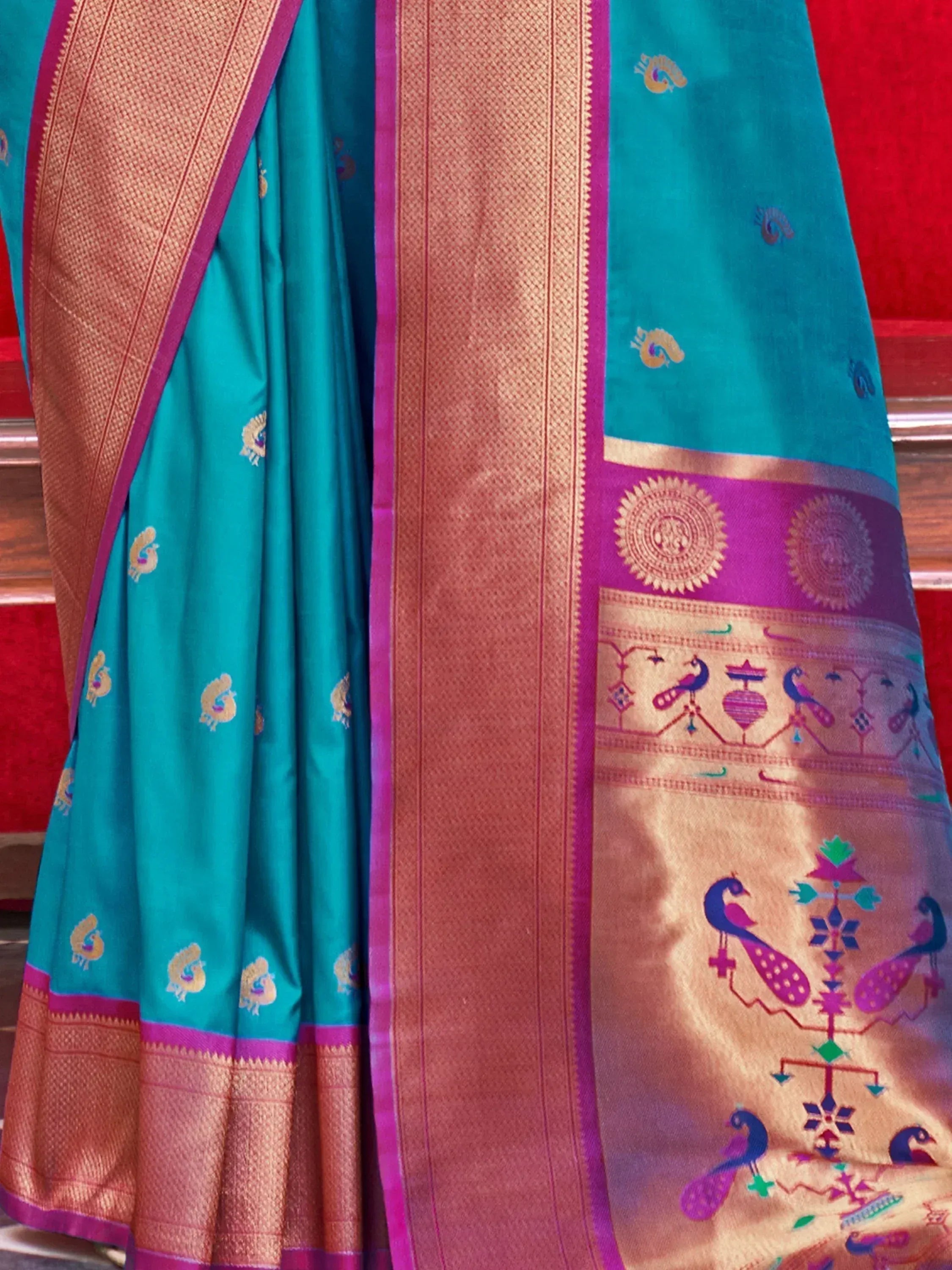 Teal silk saree with peacock motifs, gold border, and purple accents for ethnic wear