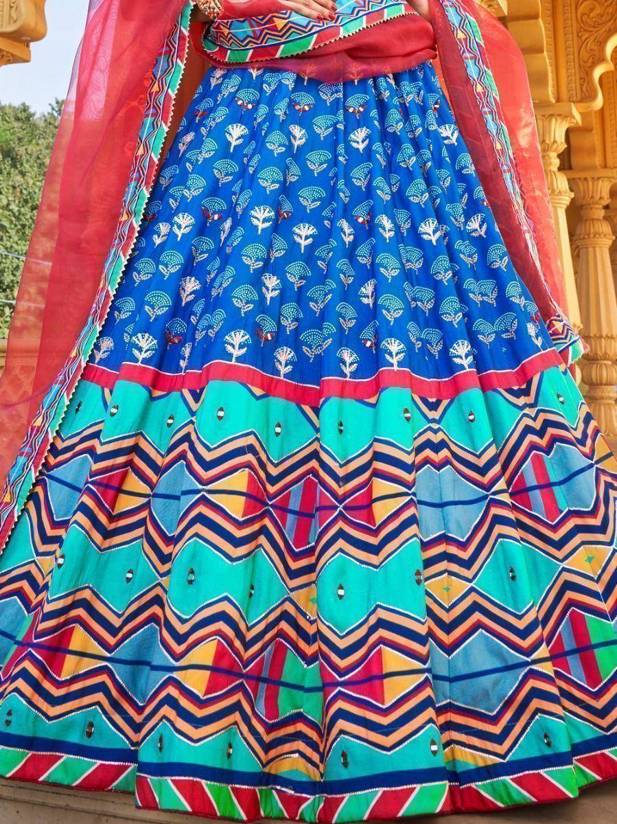 Vibrant blue and turquoise lehenga with geometric prints and mirror work, paired with red dupatta for festive Indian wear