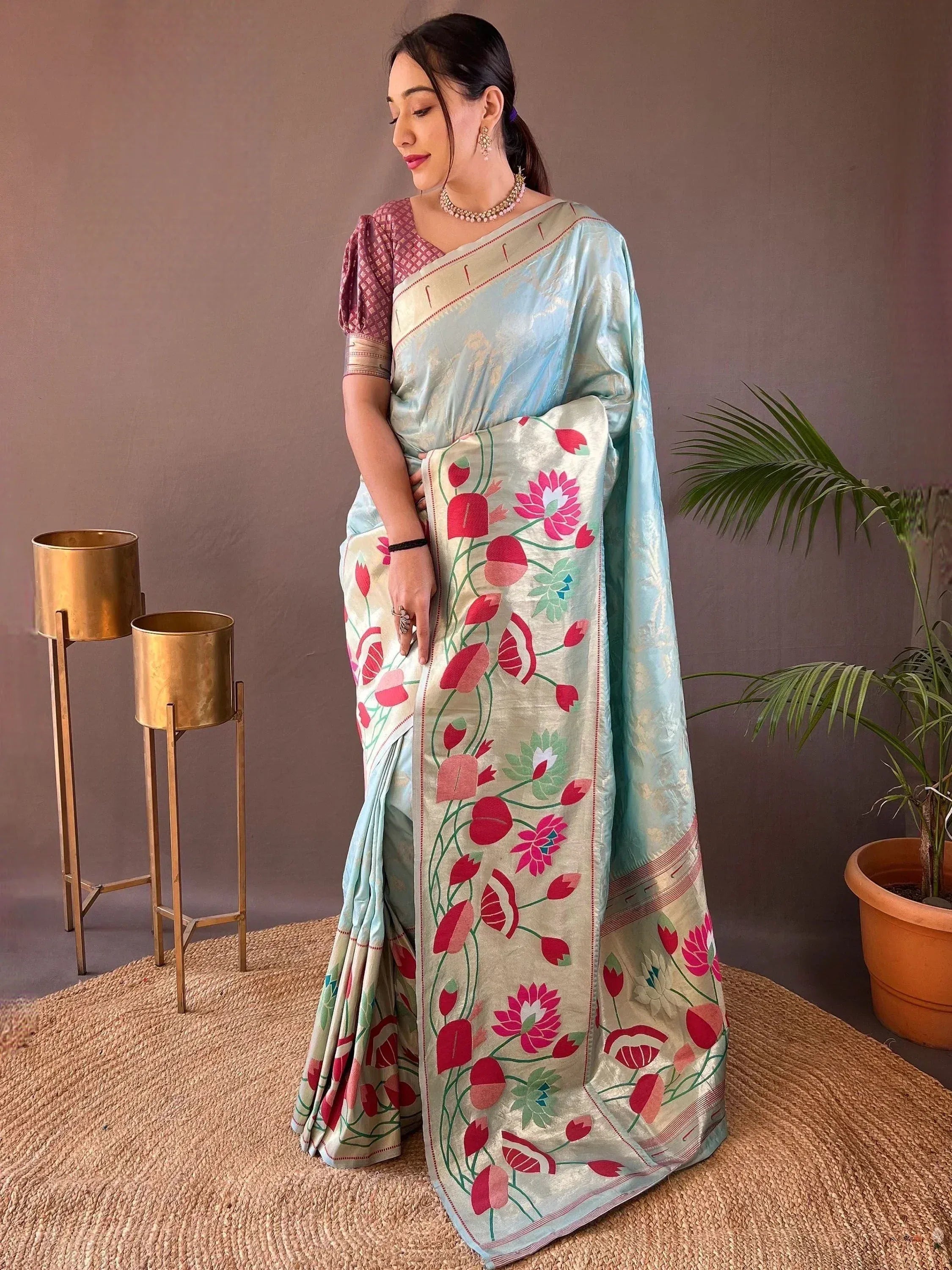 Woman in light blue floral saree with pink lotus print, paired with patterned blouse, ethnic wear