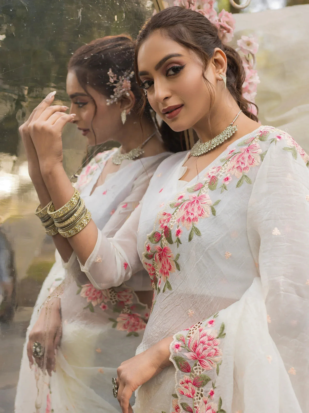 White floral embroidered ethnic gown with pink blooms, perfect for Indian weddings or festive occasions.