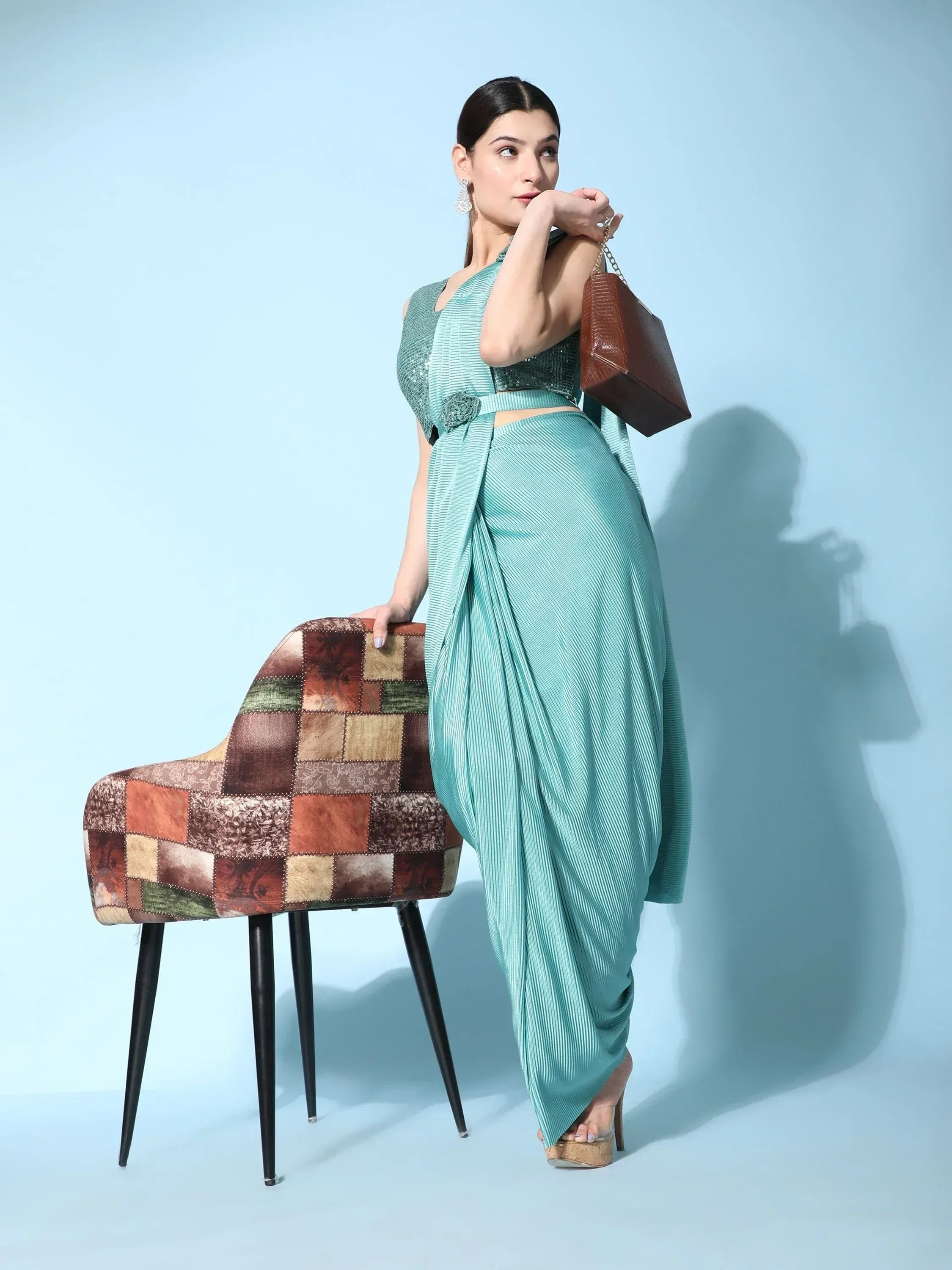 Woman in mint green pleated dhoti saree with sequin blouse, styled with brown handbag and heels