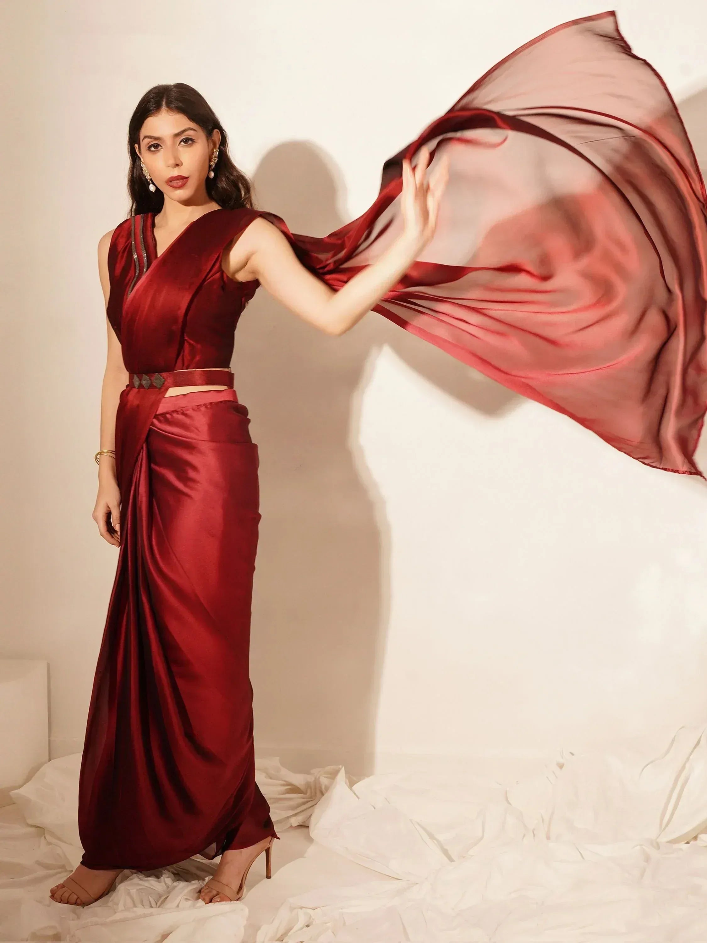 Woman in maroon satin ethnic gown with flowing dupatta, stylish Indian wear for special occasions
