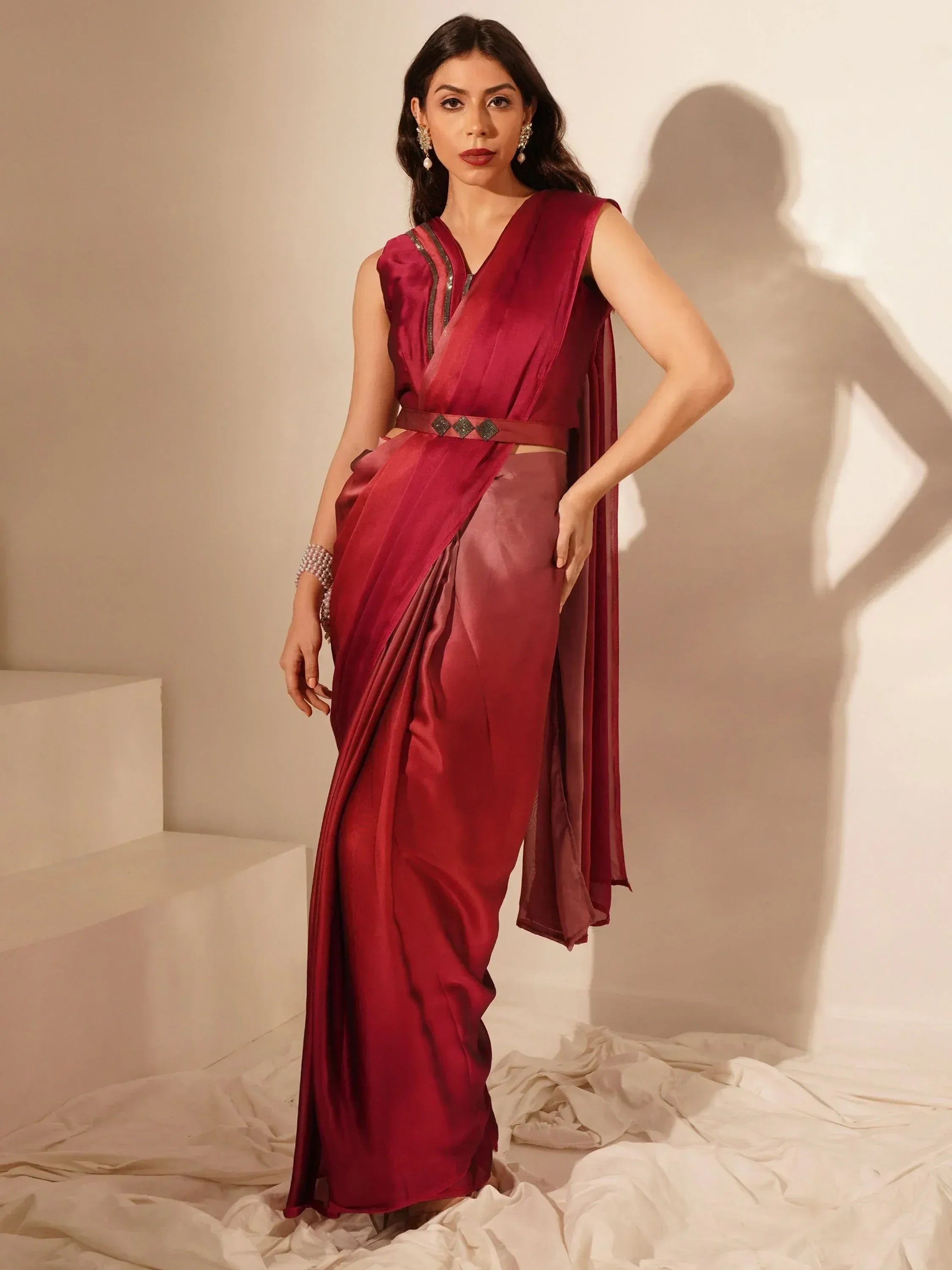 Elegant maroon saree with sleeveless blouse and embellished belt, perfect for Indian ethnic occasions.