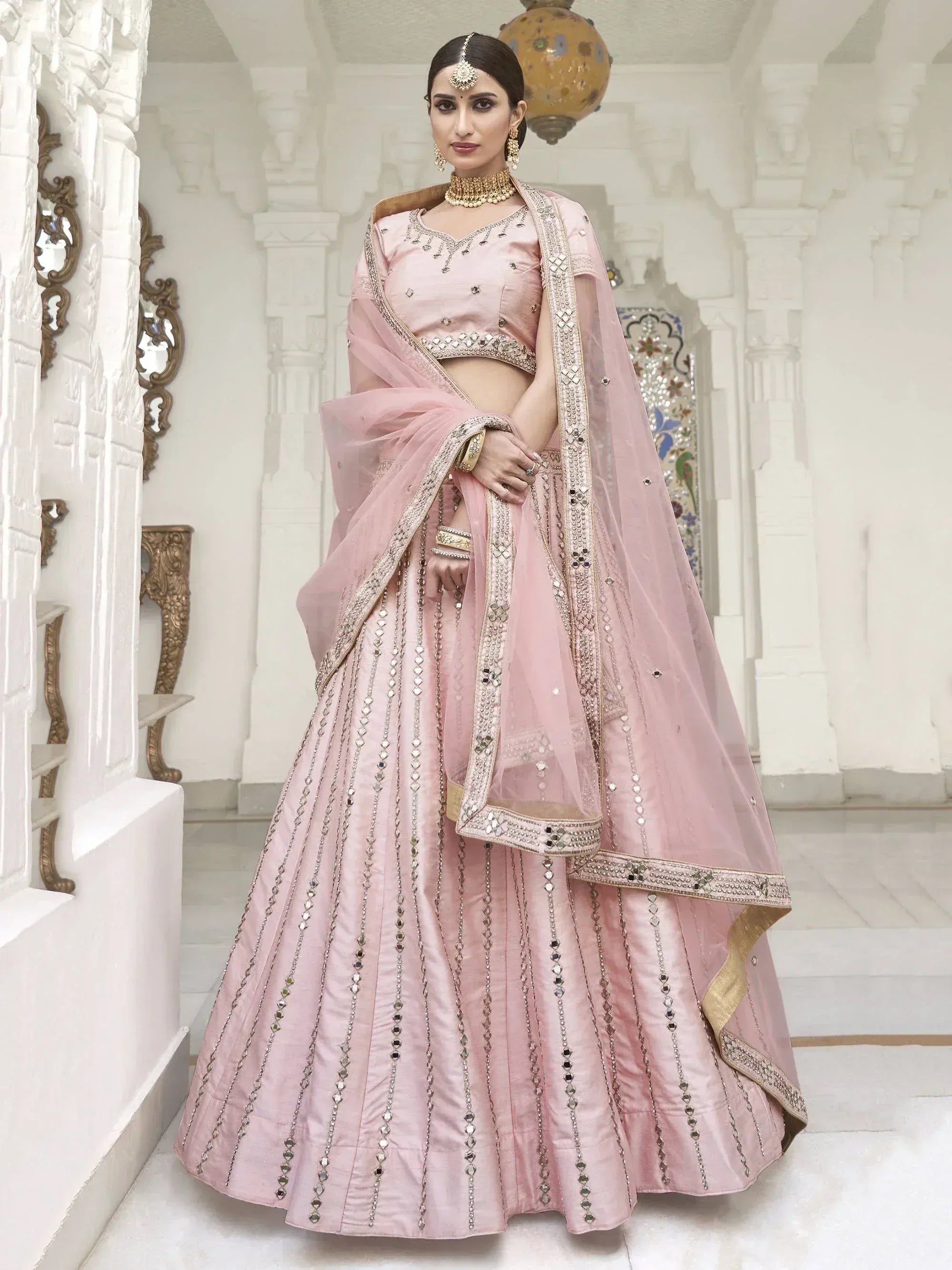 Pink designer lehenga choli with mirror work and gold trim, perfect for Indian weddings and festive occasions