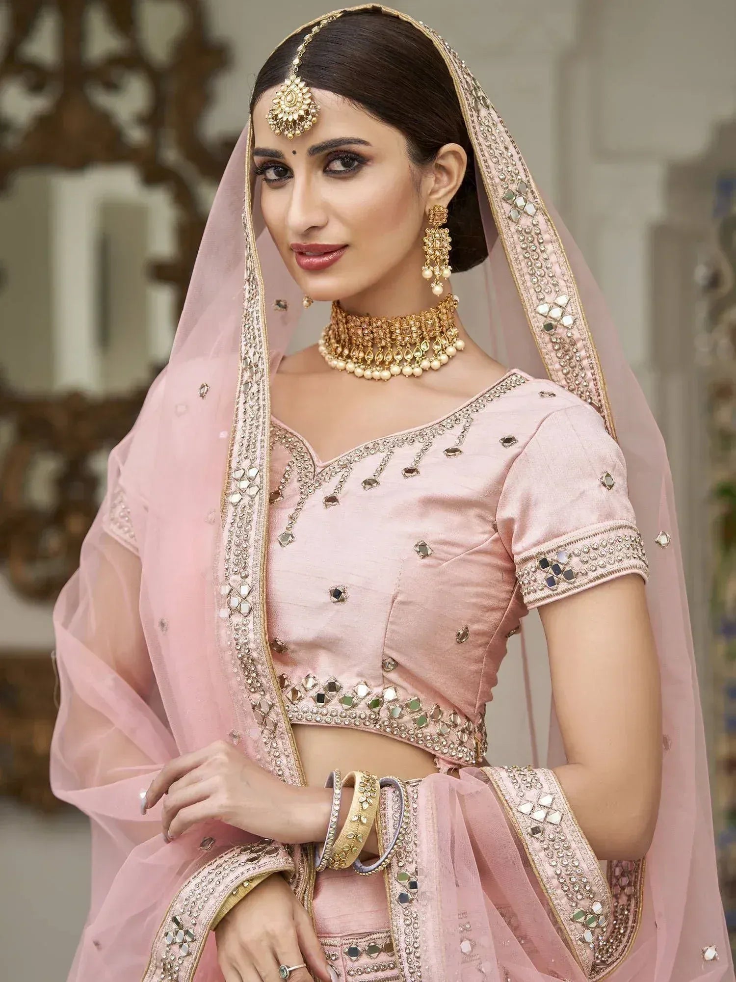 Pink designer lehenga choli with mirror work, gold jewelry, and dupatta for Indian ethnic wear