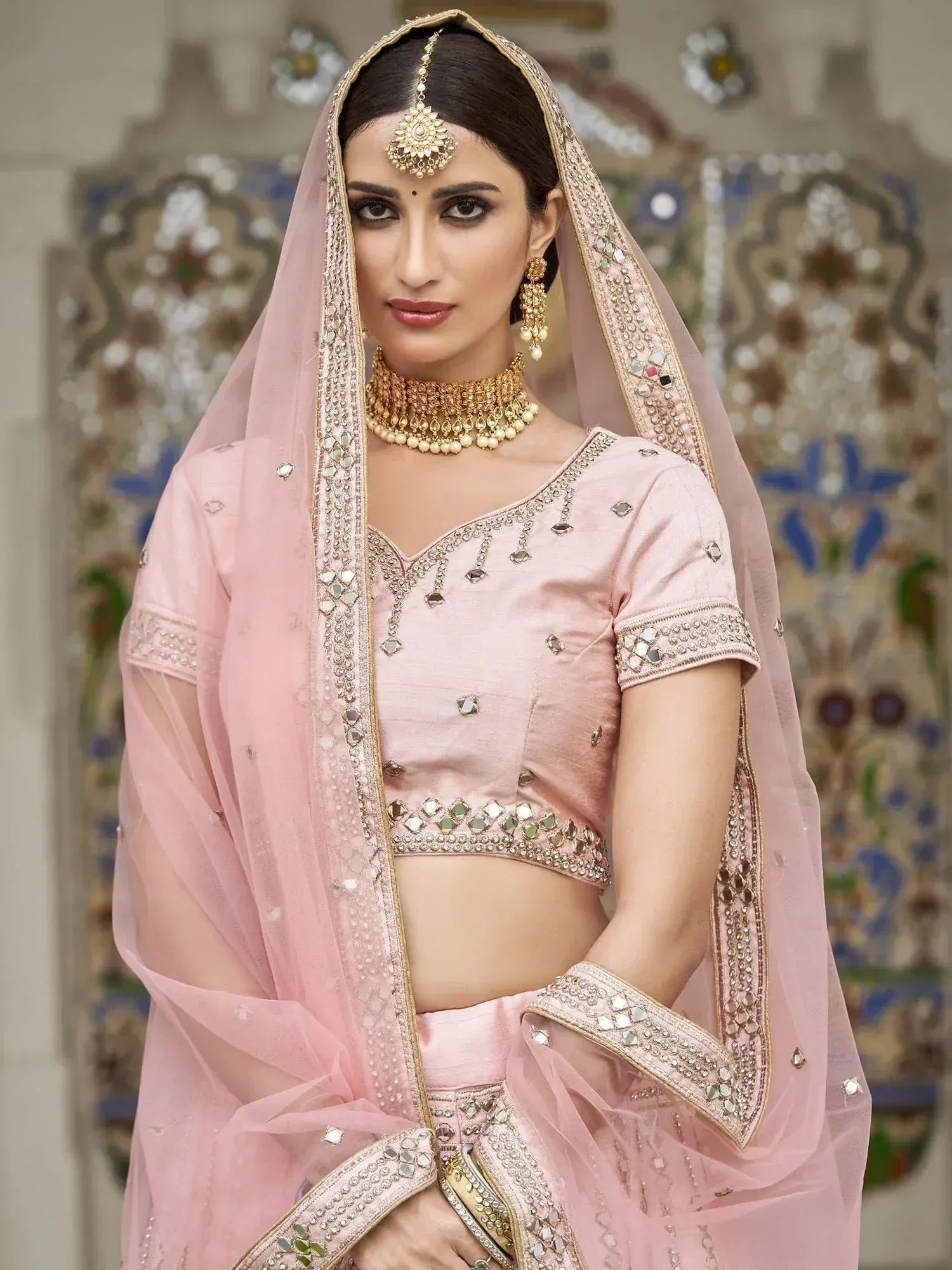 Pink designer lehenga choli with mirror work and gold jewelry for Indian weddings