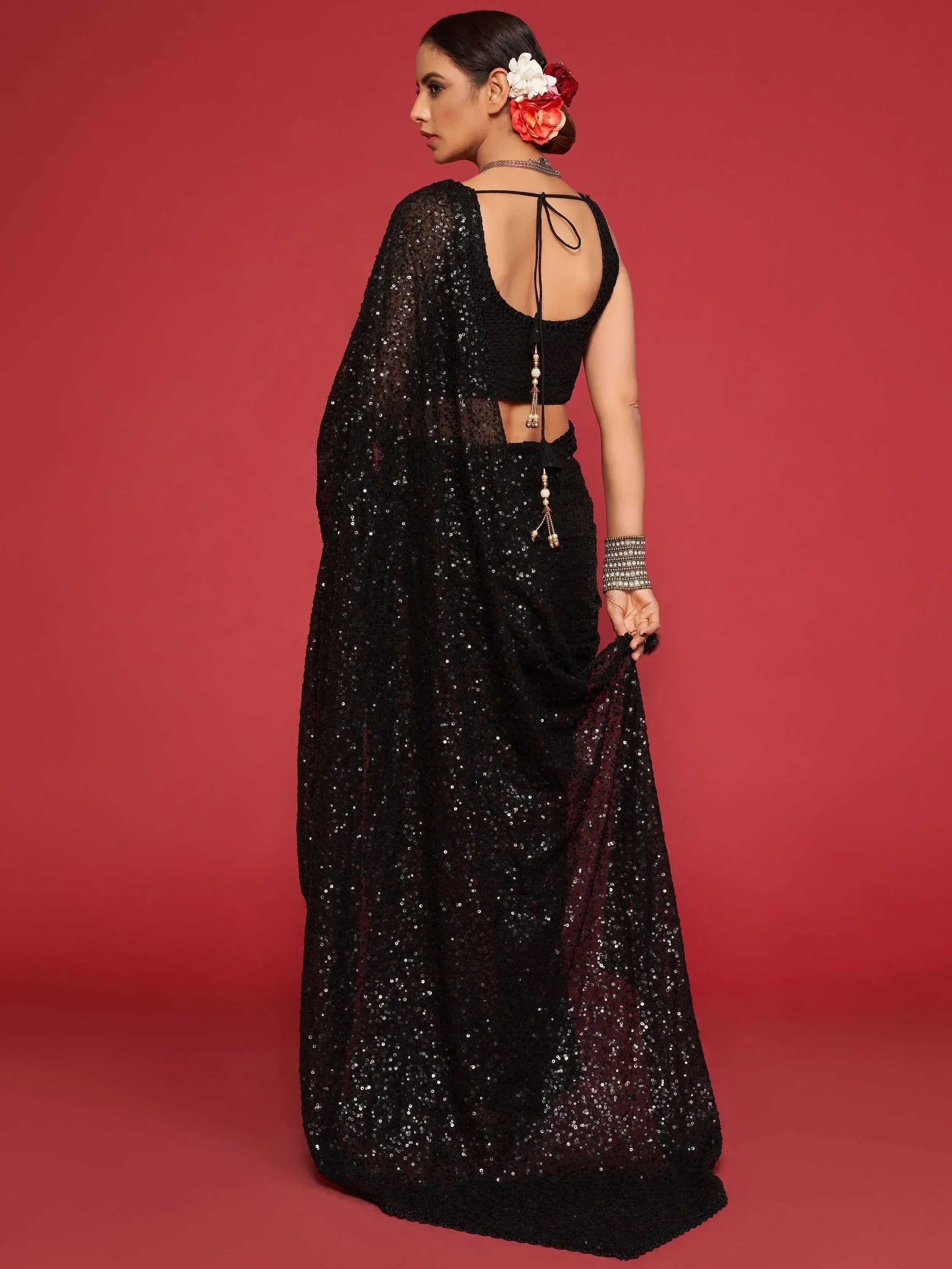 Black sequin lehenga choli with back tie detail, floral hair accessory, and statement jewelry