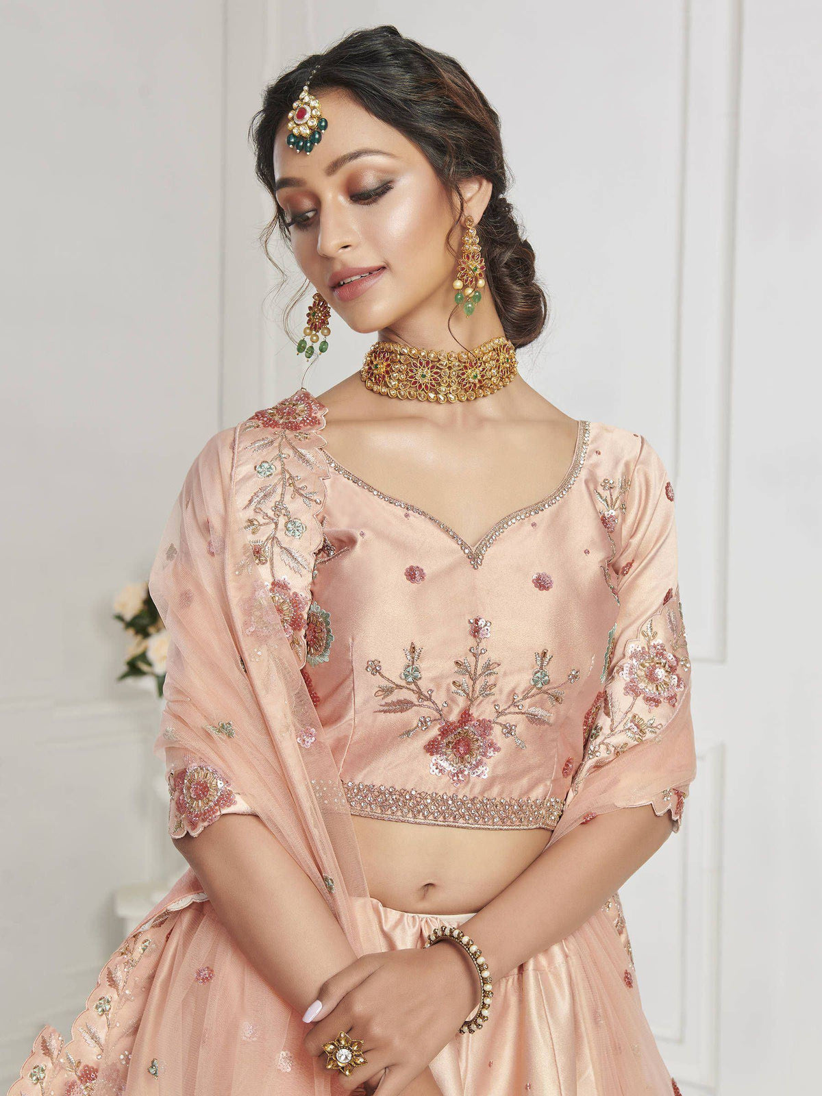 Pink embroidered lehenga choli with floral motifs, matching dupatta, and traditional Indian jewelry for weddings