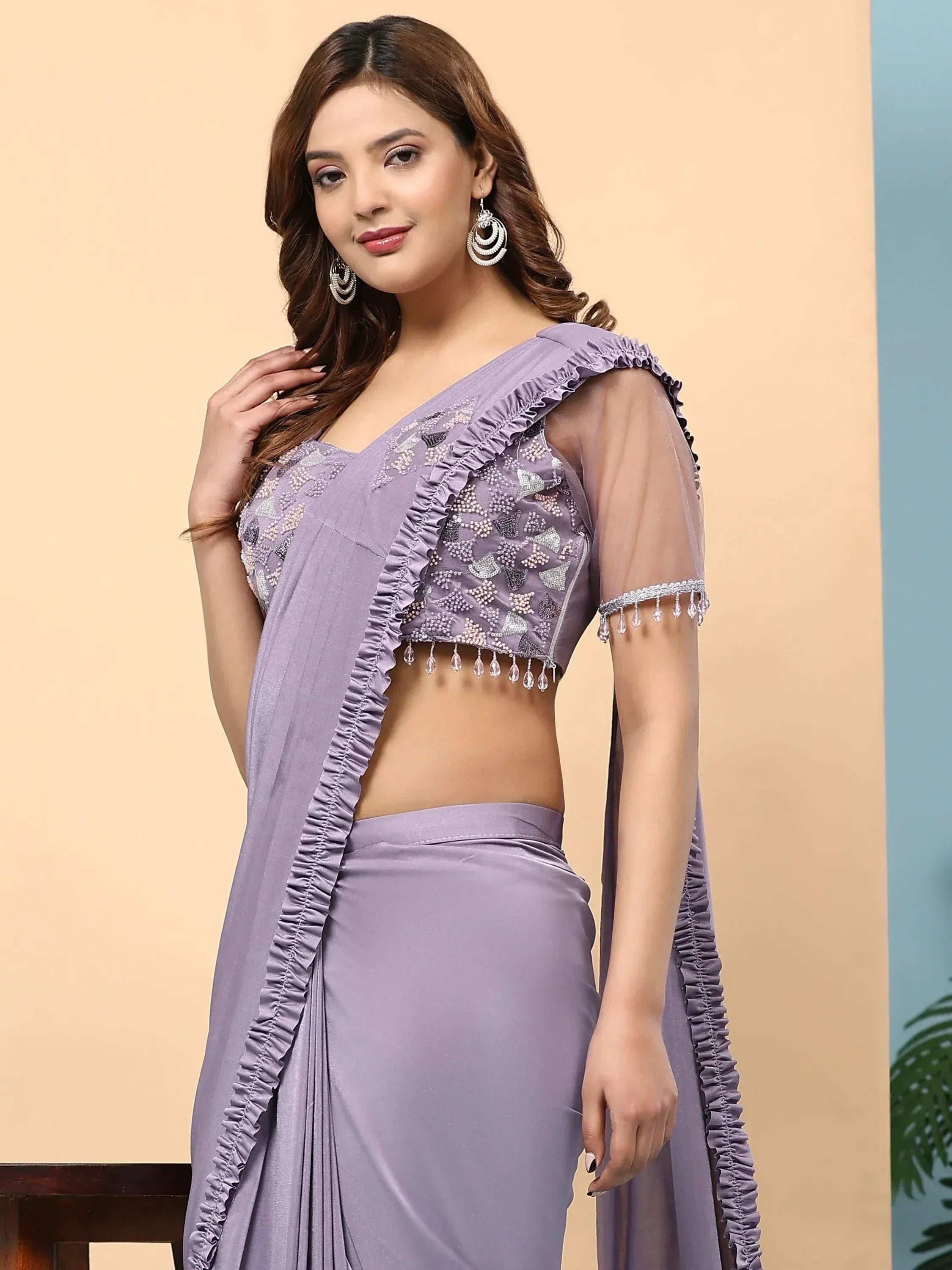 Lavender ethnic saree with ruffled blouse, crystal embellishments, and sheer sleeves for festive occasions