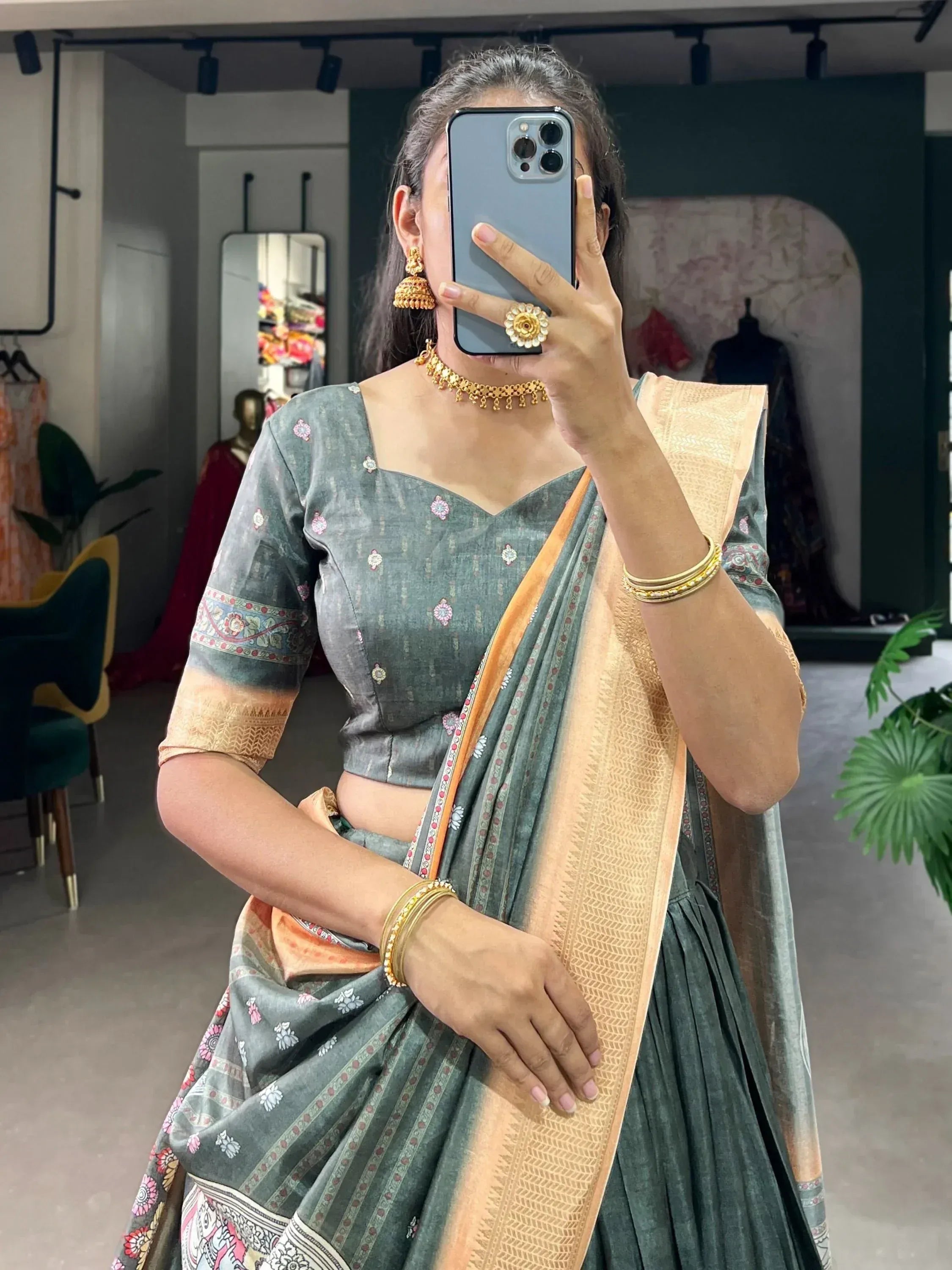 Elegant green saree with floral motifs and golden border, paired with traditional jewelry