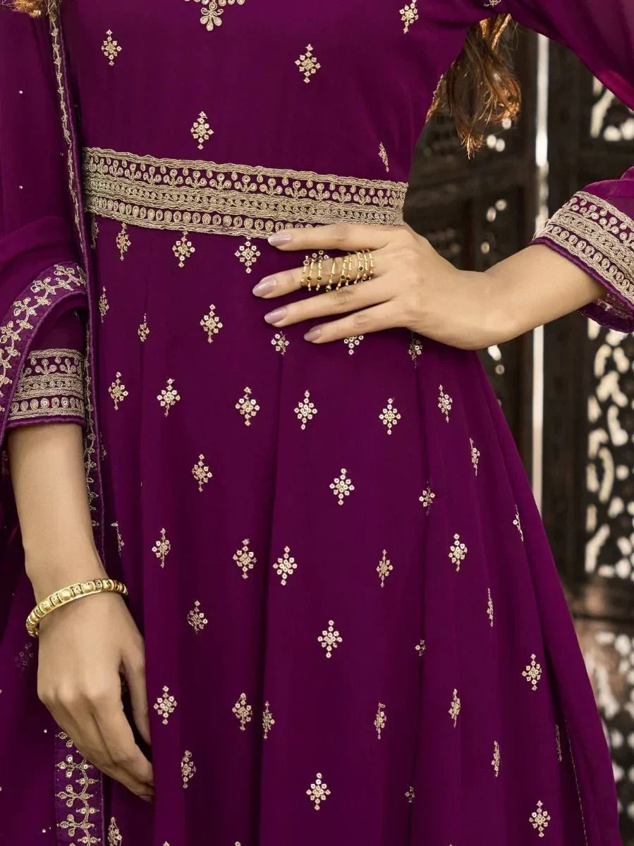 Woman wearing purple embroidered Indian ethnic gown with gold jewelry details