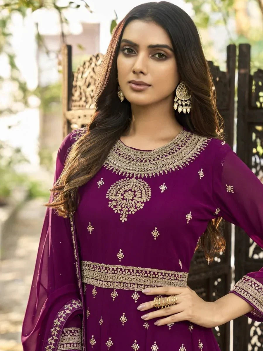 Woman wearing purple embroidered ethnic gown with gold jewelry outdoors