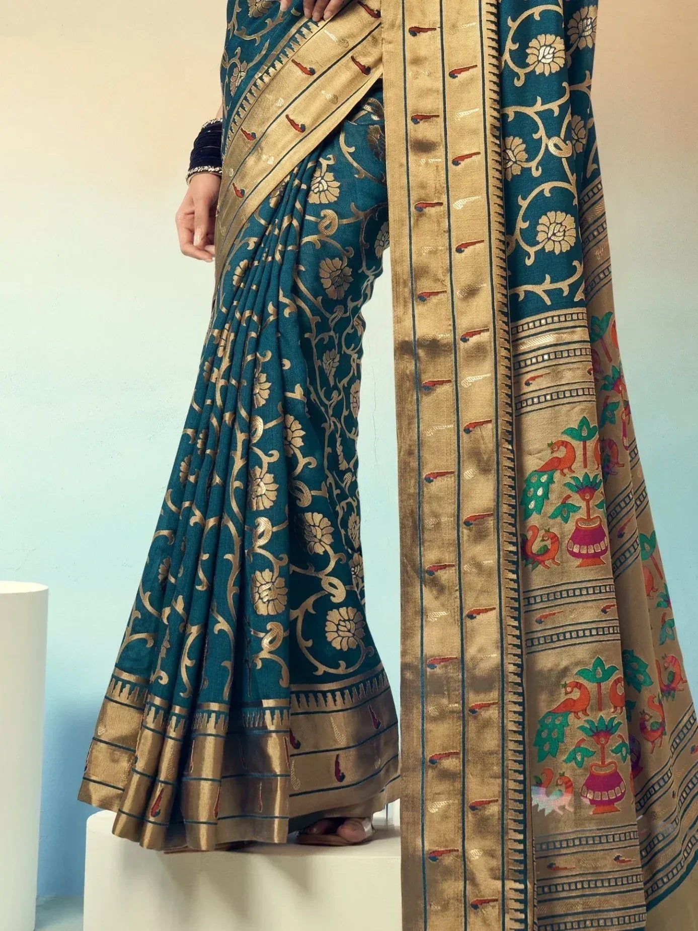 Teal and gold designer saree with floral and peacock motifs, perfect for ethnic occasions