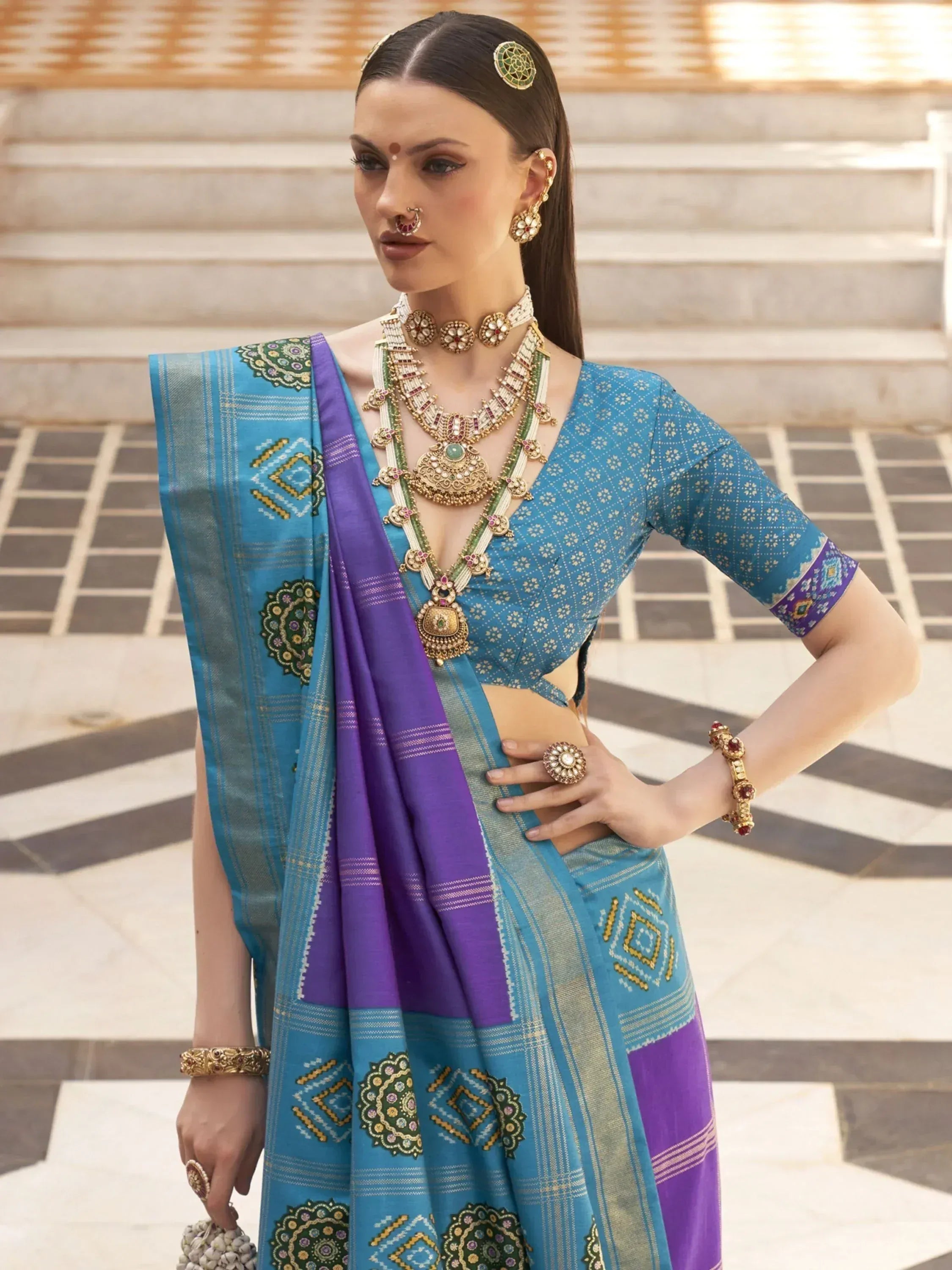 Blue and purple ethnic saree with intricate embroidery, paired with traditional jewelry for festive occasions.