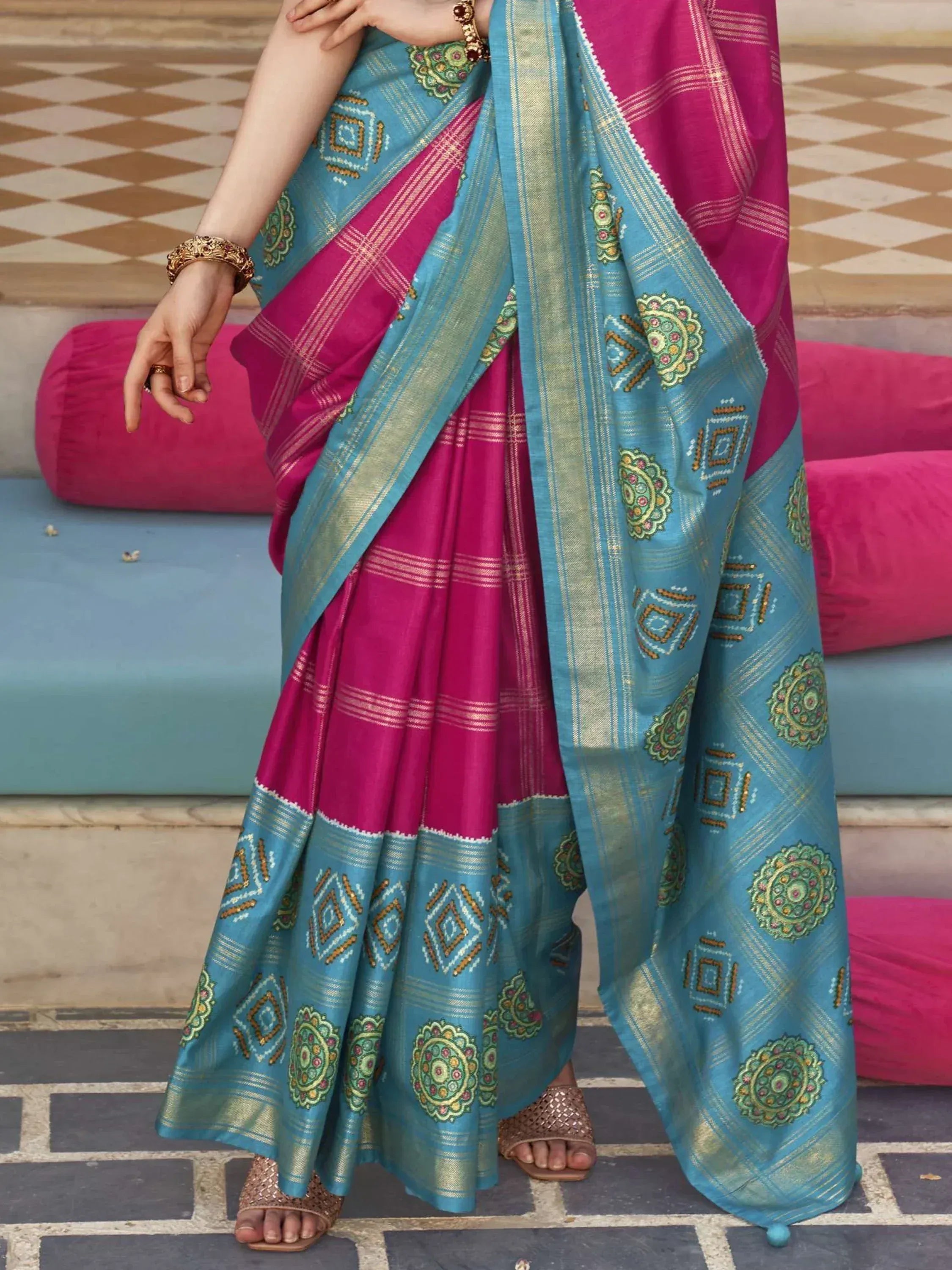 Pink and turquoise ethnic saree with embroidered motifs and gold border, styled for traditional occasions