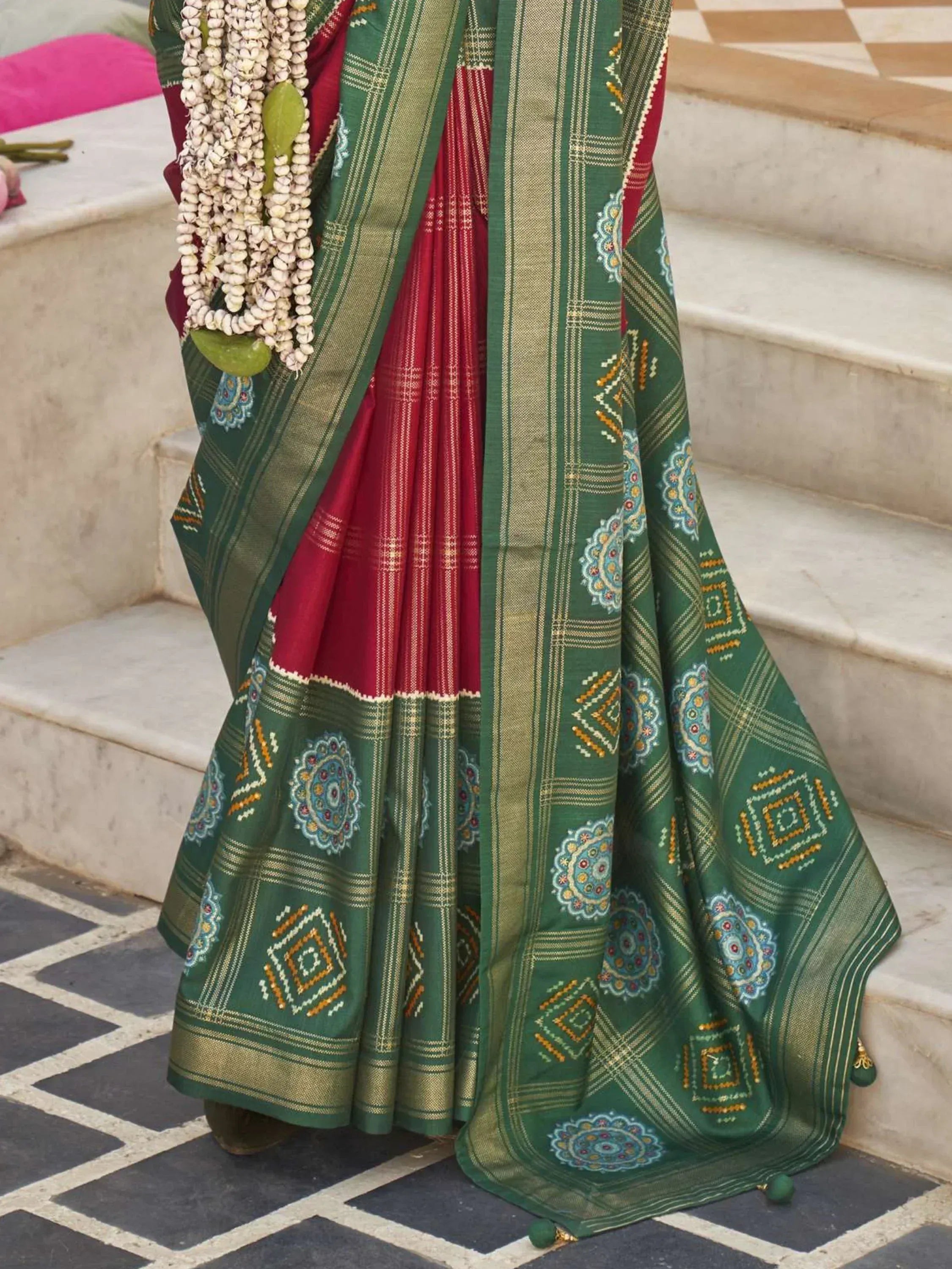 Green and red ethnic saree with intricate geometric and floral patterns, perfect for traditional occasions.
