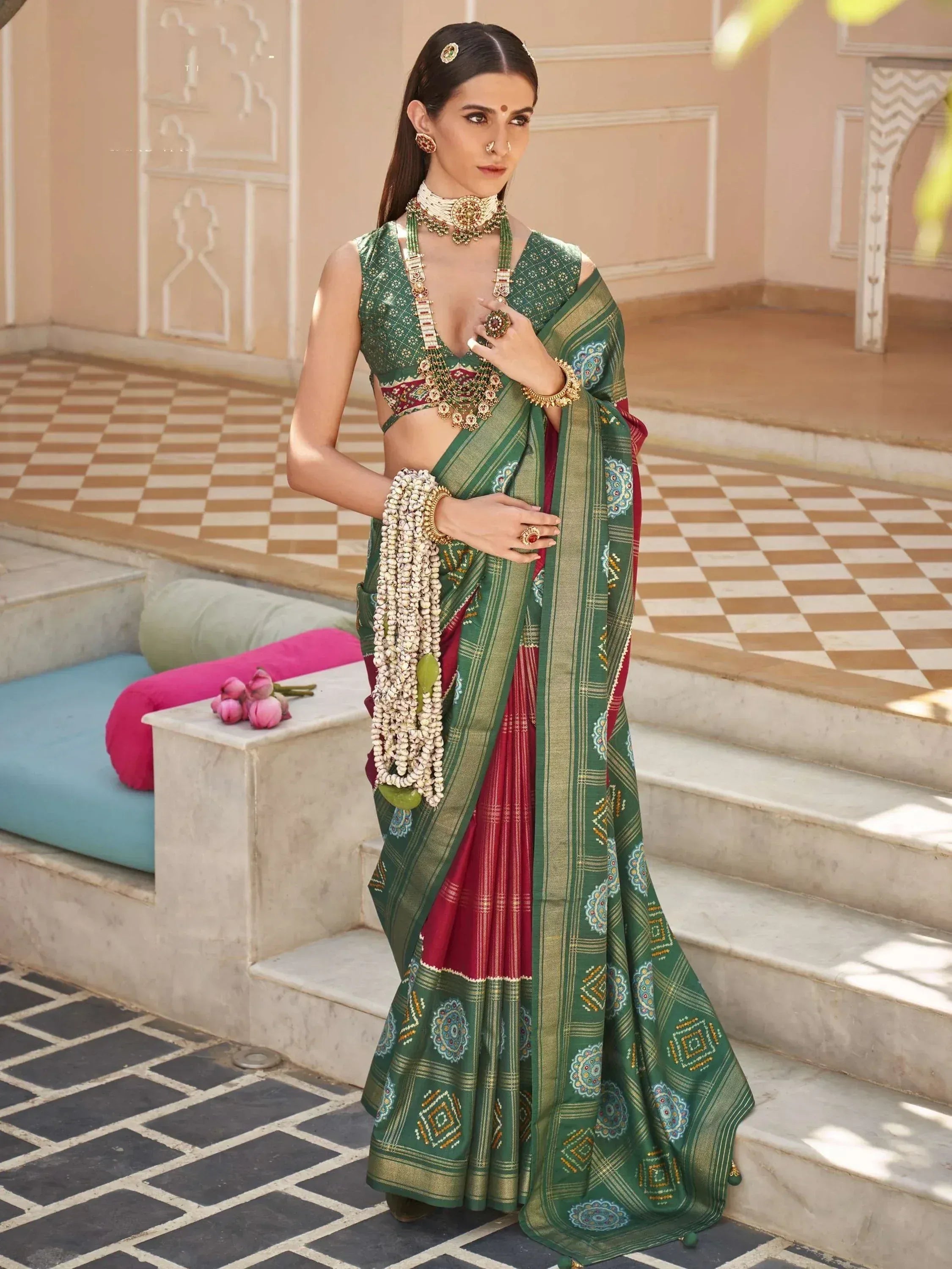 Green and red ethnic saree with intricate patterns, paired with traditional jewelry and blouse, perfect for Indian occasions.