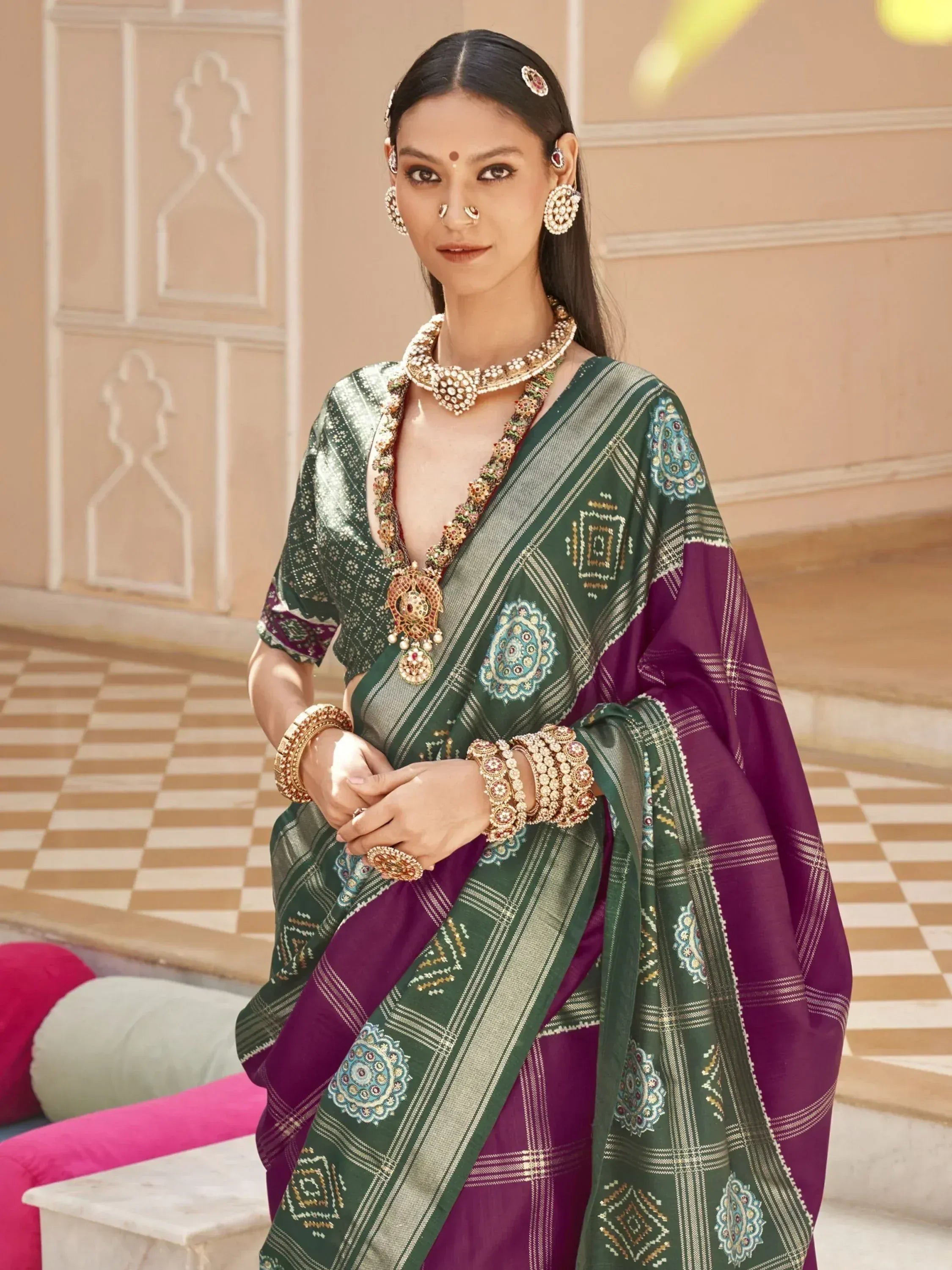 Woman in green and purple embroidered saree with traditional Indian jewelry, perfect for ethnic occasions.