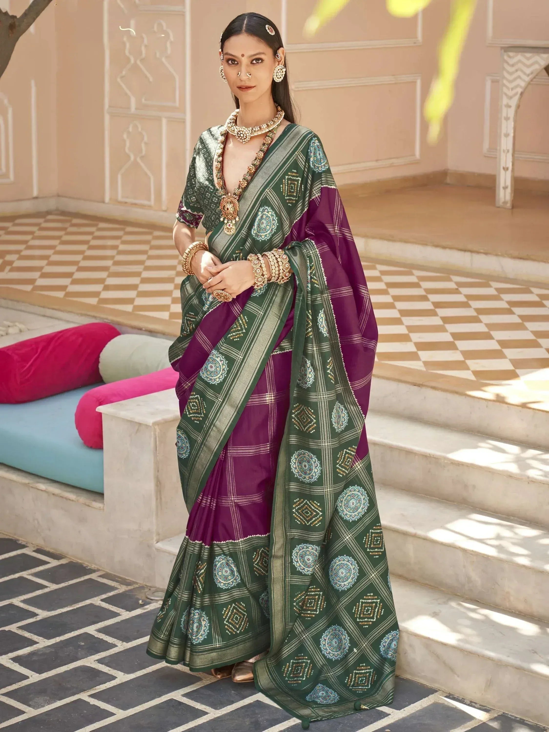 Woman in green and purple ethnic saree with intricate embroidery, traditional Indian jewelry, and designer blouse.