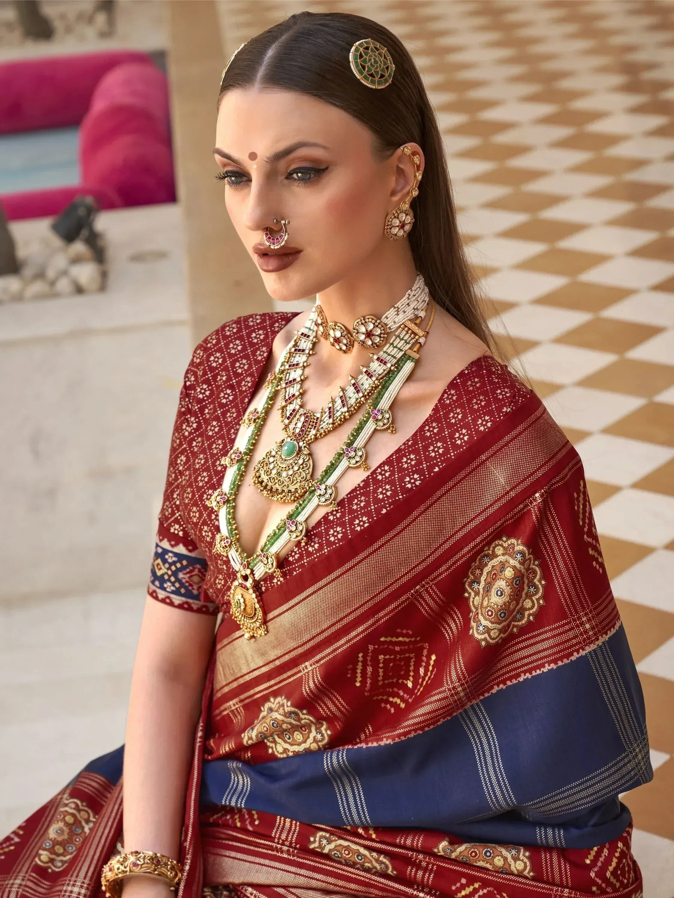 Woman in maroon and blue ethnic saree with gold jewelry, traditional Indian attire