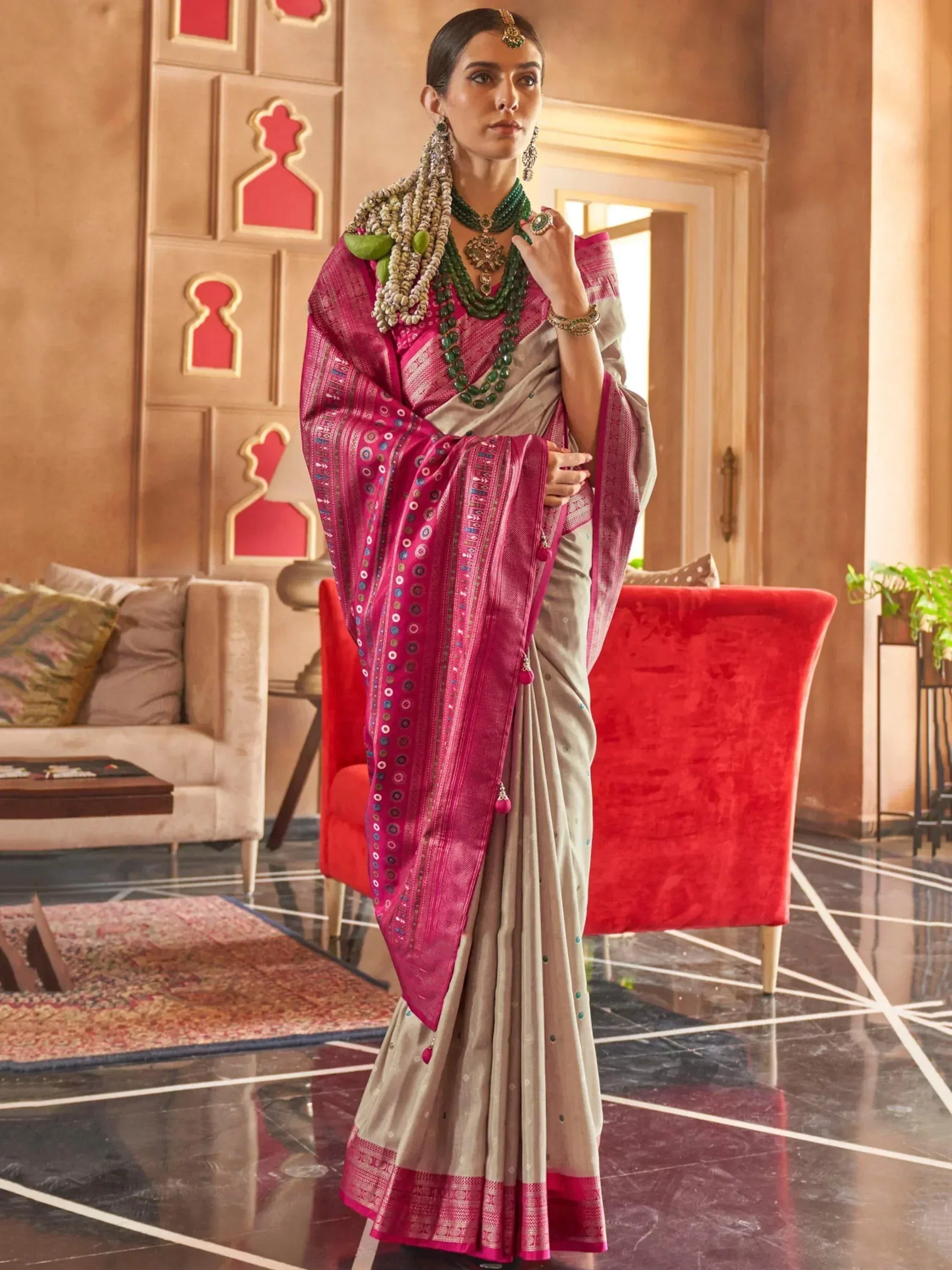 Elegant woman in designer saree with pink border, traditional jewelry, and ethnic decor