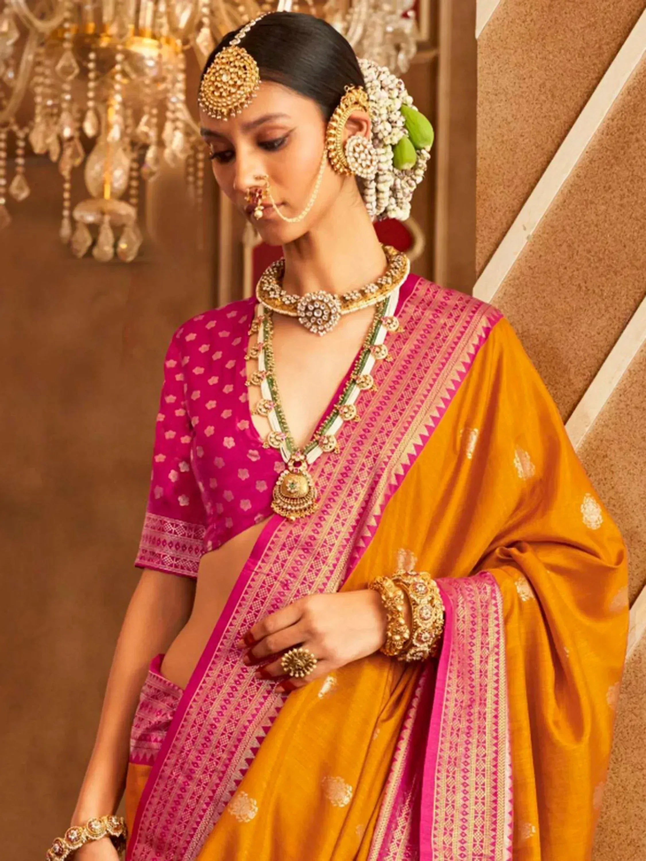 Woman in vibrant pink and mustard yellow saree with gold jewelry, traditional Indian ethnic wear