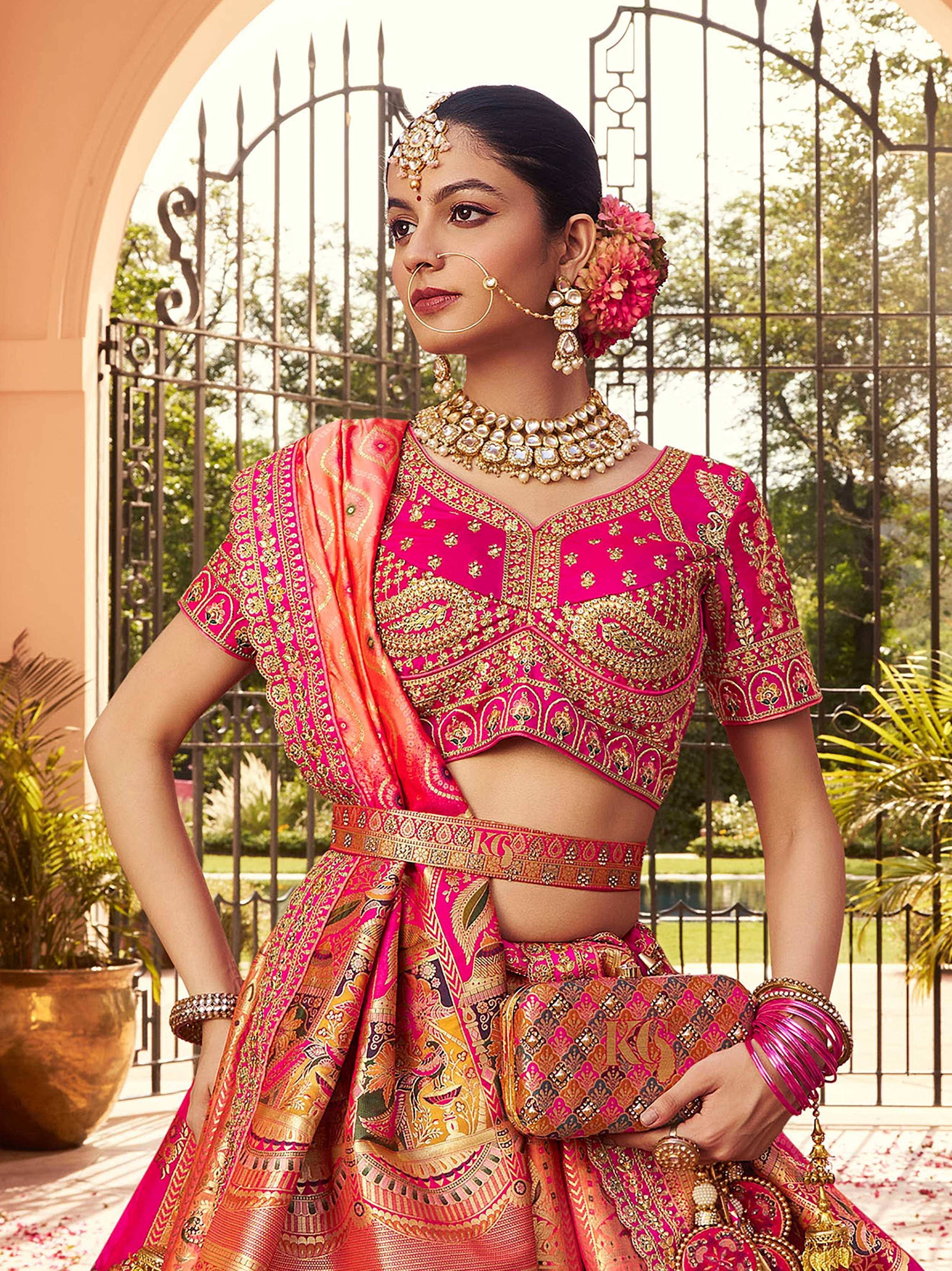Pink and gold embroidered lehenga choli with traditional Indian jewelry and floral hair accessory
