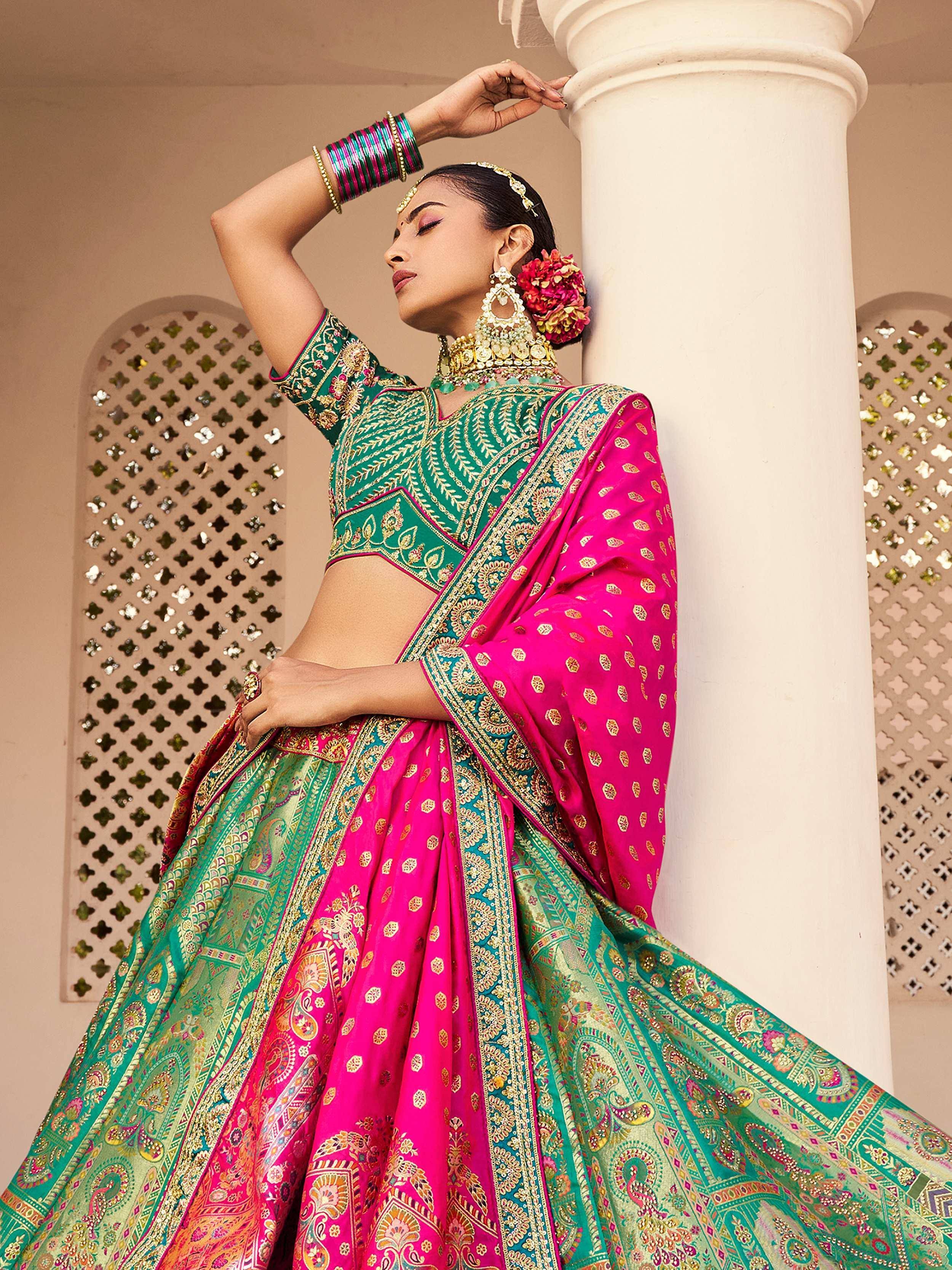 Woman in vibrant pink and green designer lehenga choli with gold embroidery, perfect for Indian ethnic wear.