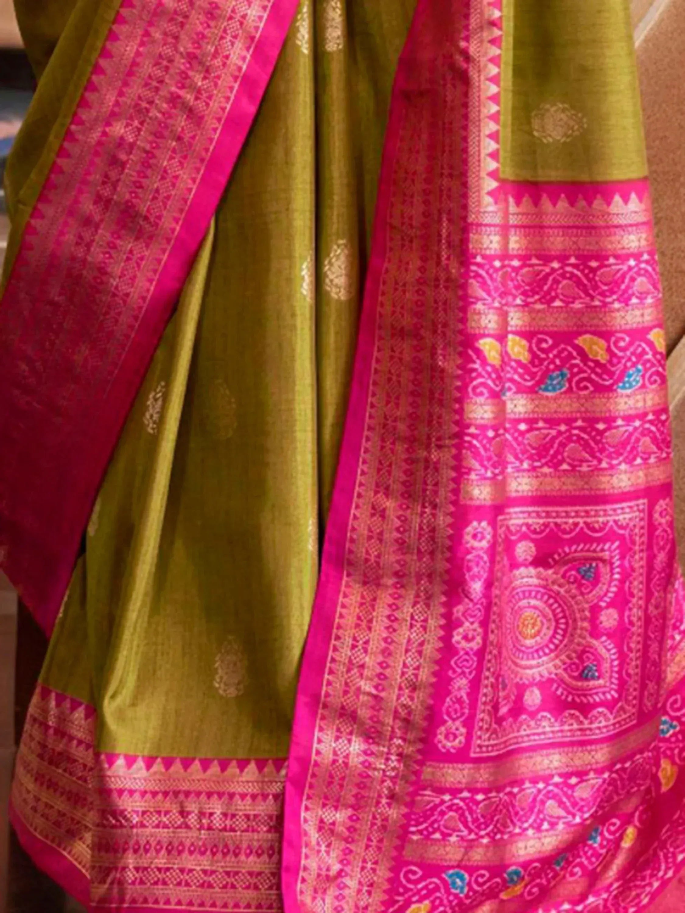 Vibrant pink and olive green Indian saree with intricate gold zari border and traditional paisley motifs