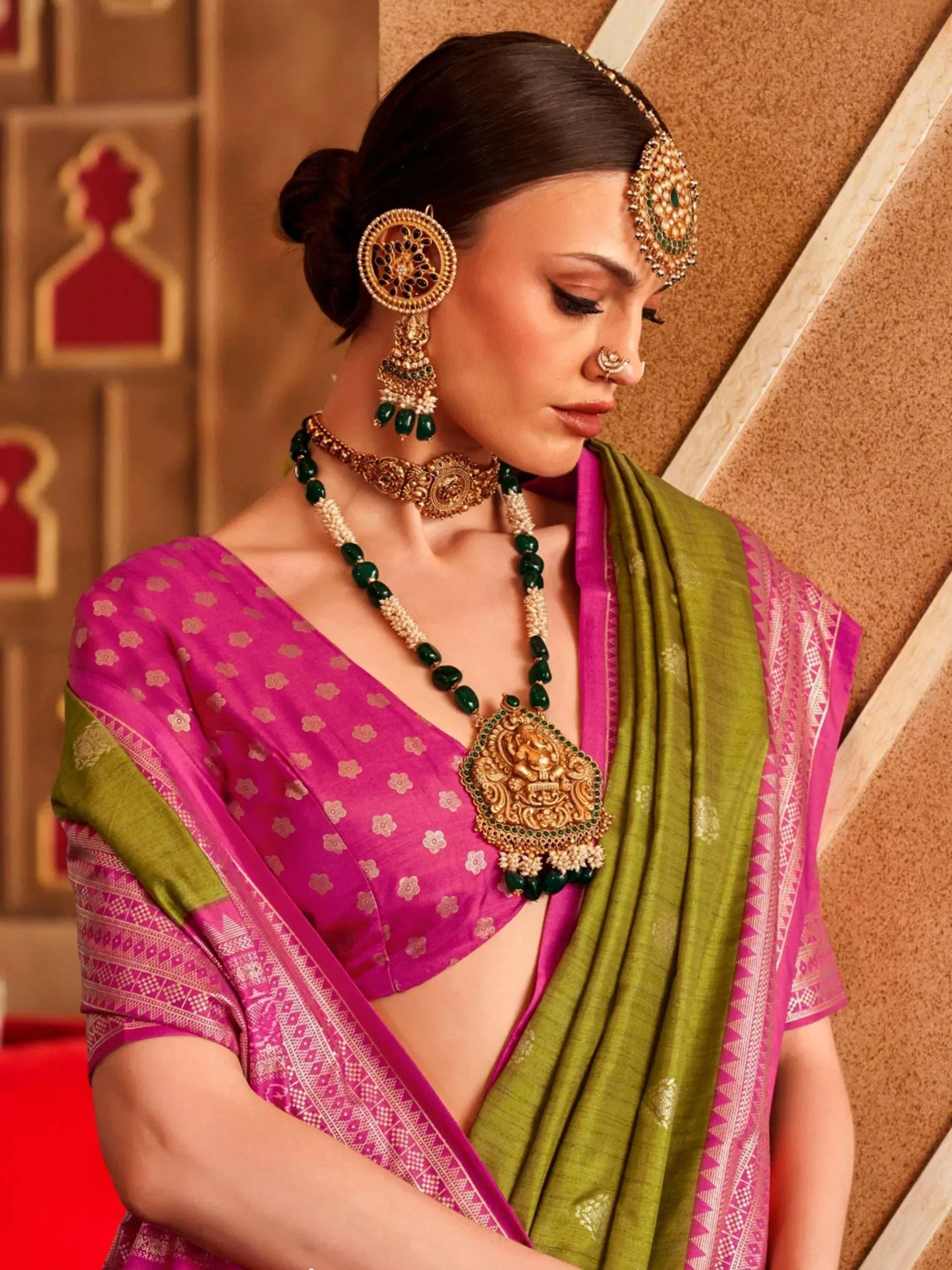 Woman in pink and green ethnic saree with gold jewelry, traditional Indian attire