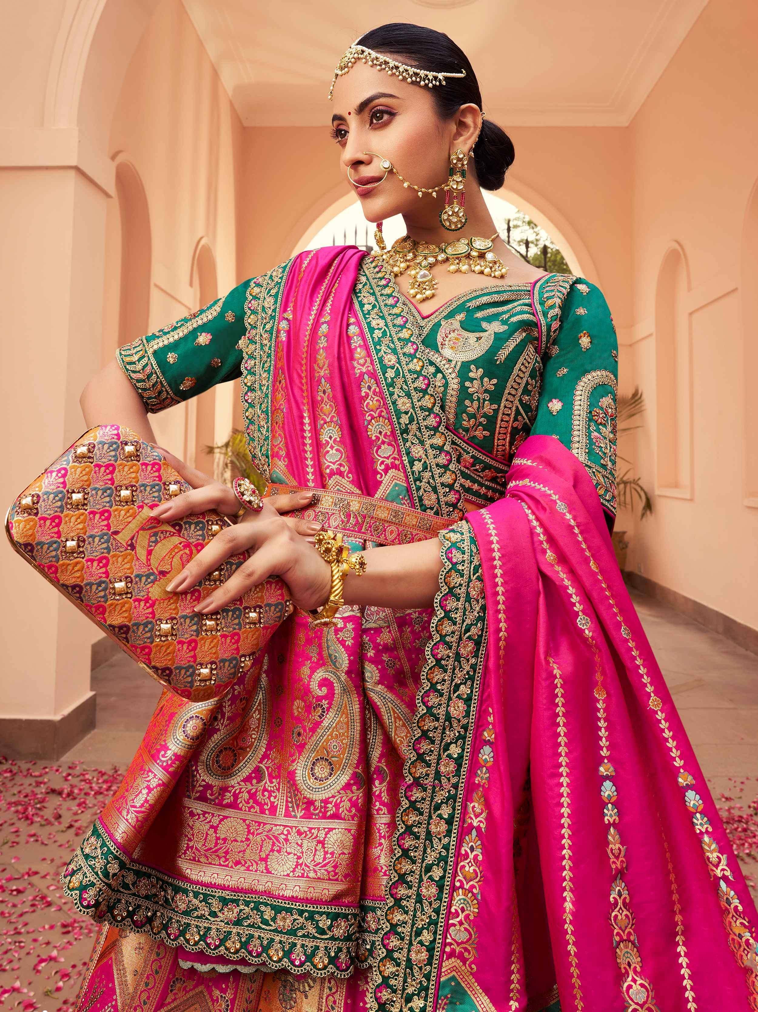 Elegant green and pink embroidered Indian ethnic wear with traditional jewelry and clutch, perfect for festive occasions.