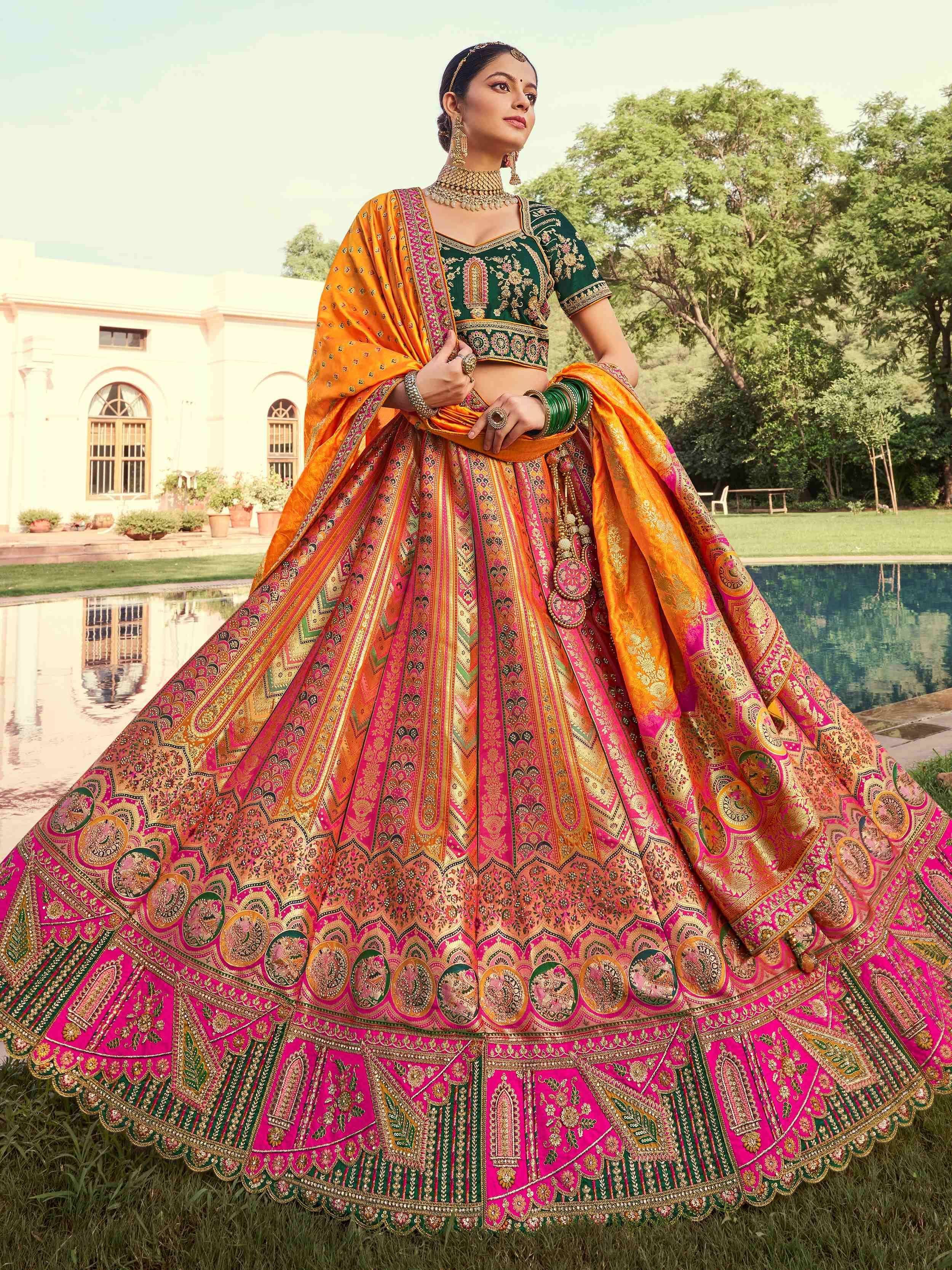 Woman in vibrant pink and green designer lehenga choli with intricate embroidery, perfect for Indian weddings and festive occasions.