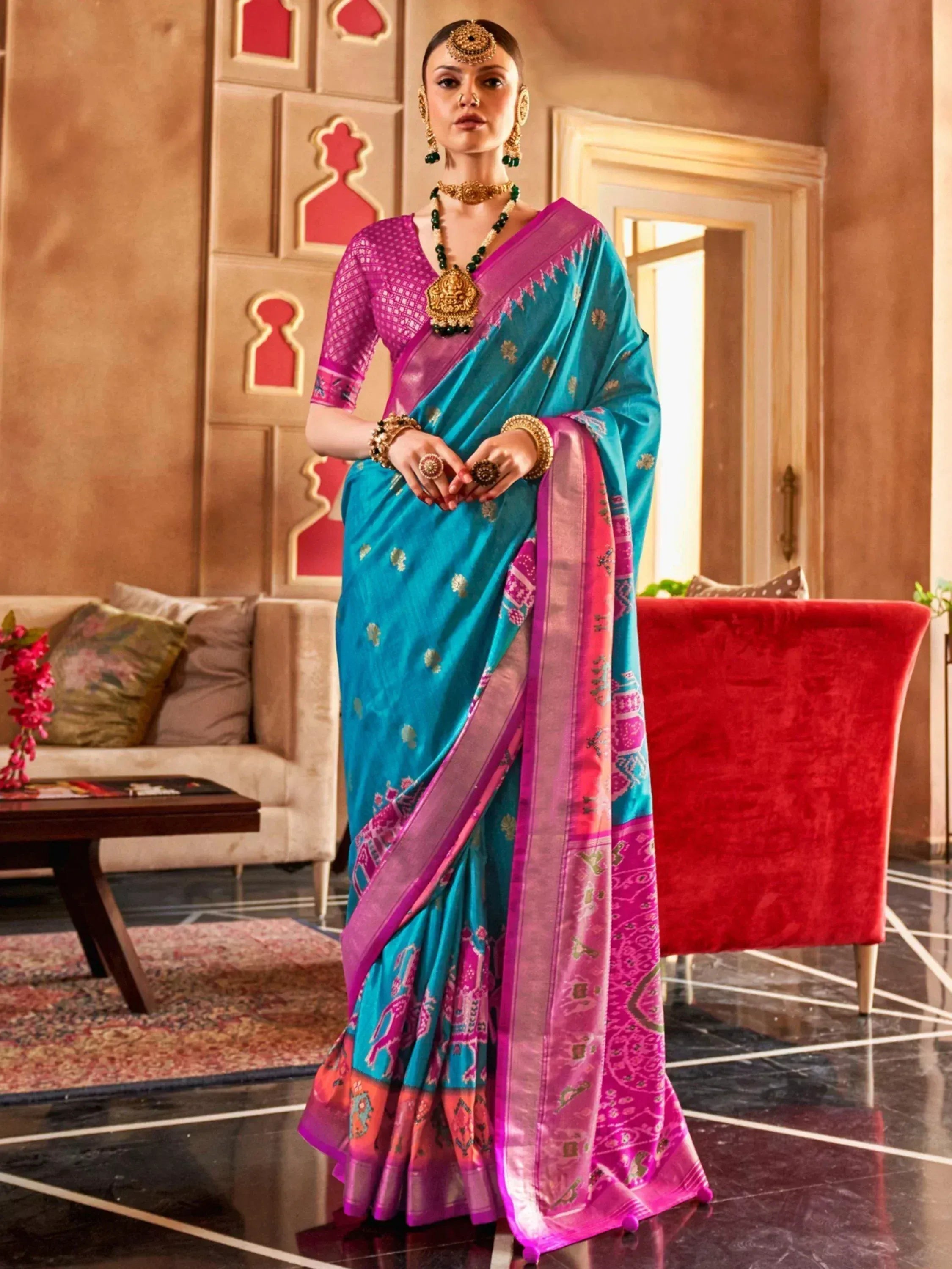 Turquoise and pink designer saree with gold motifs, paired with ethnic jewelry for festive occasions