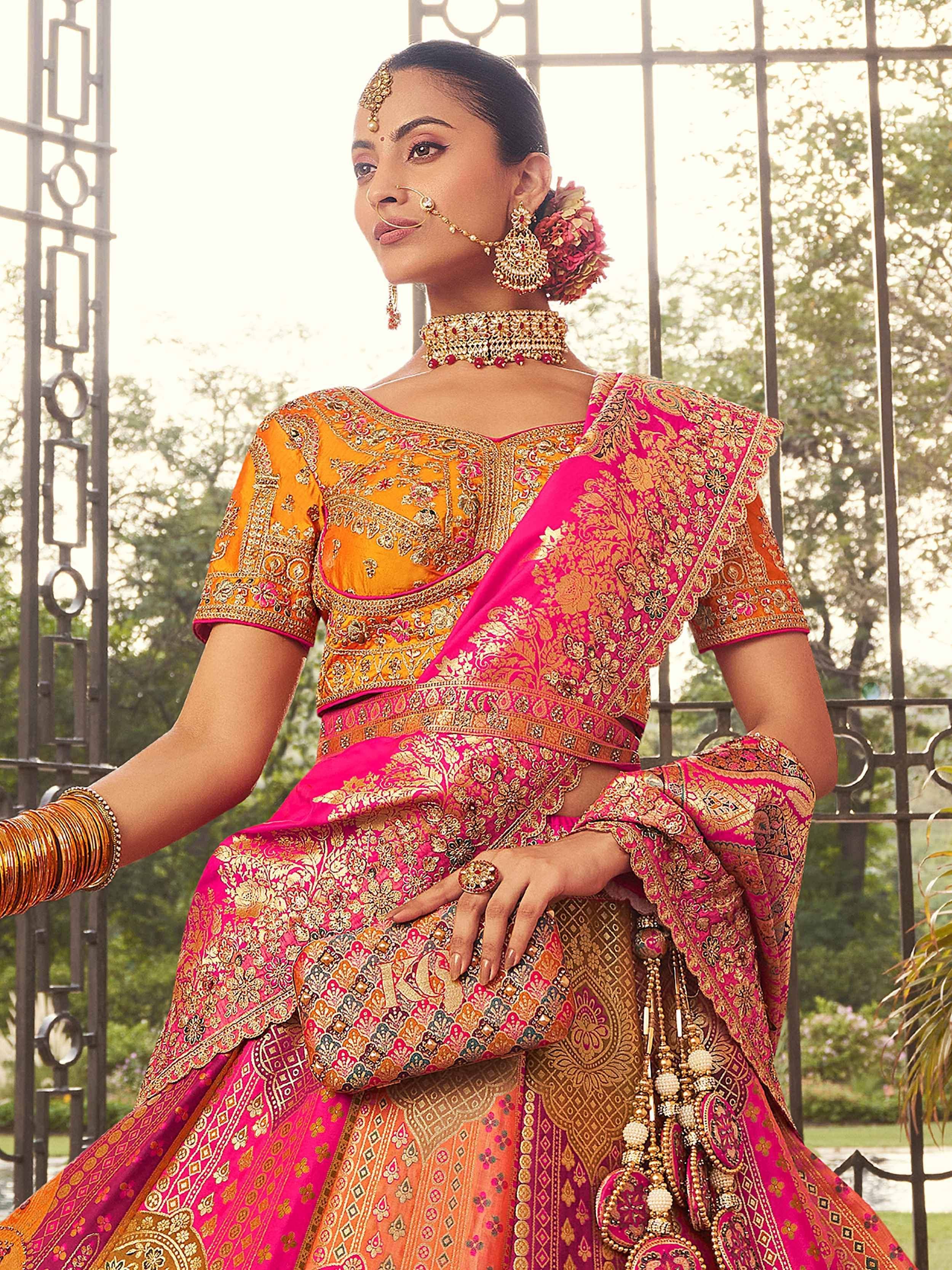 Elegant Indian lehenga choli in vibrant pink and orange with intricate gold embroidery, perfect for weddings and festive occasions.