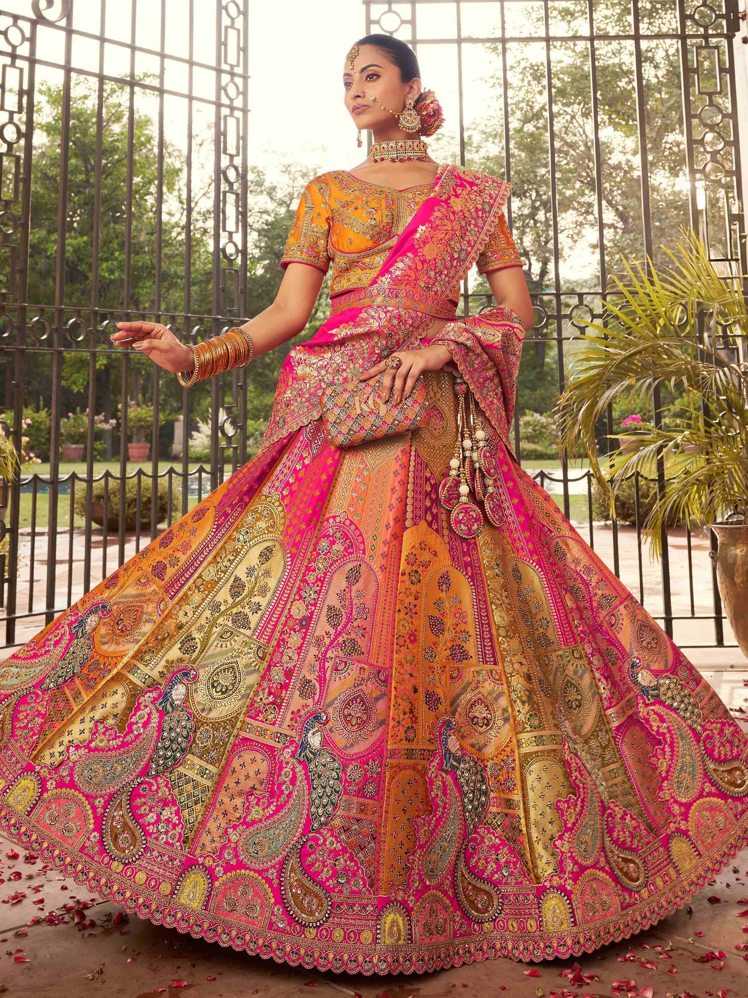 Vibrant pink and orange designer lehenga choli with intricate embroidery and peacock motifs, perfect for Indian weddings.