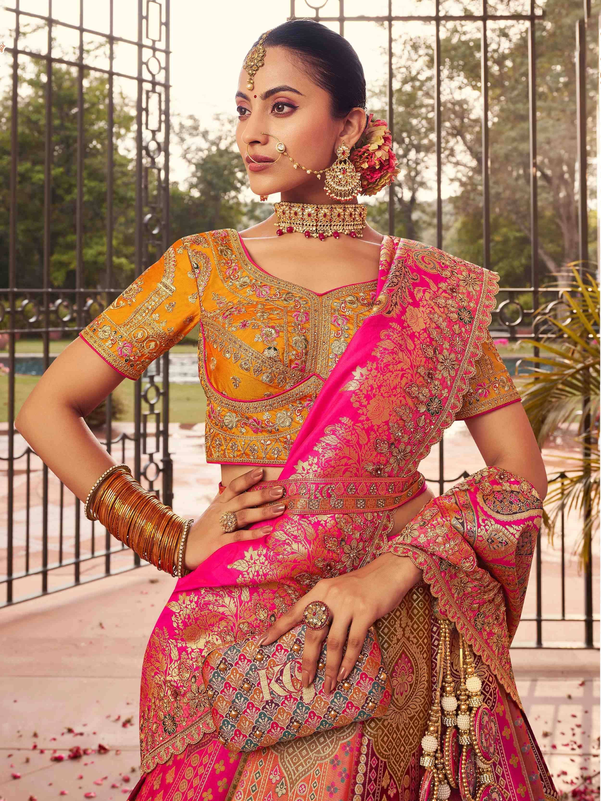 Woman in vibrant pink and gold embroidered lehenga choli with traditional Indian jewelry, perfect for weddings and festivals.
