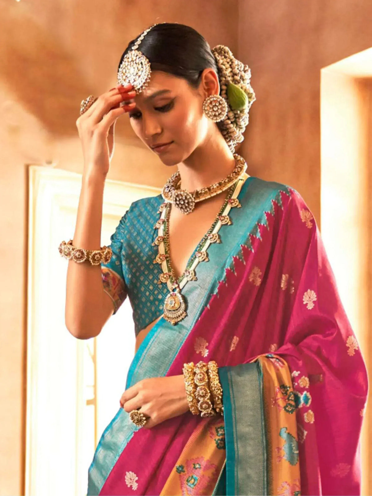 Woman in vibrant blue and pink saree with gold jewelry, traditional Indian ethnic wear