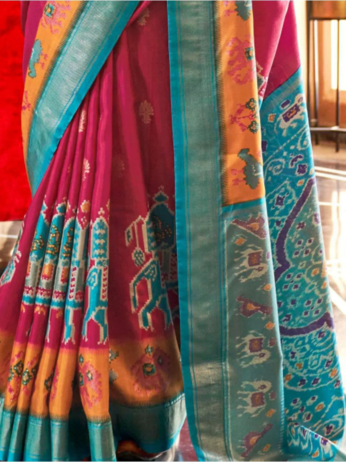Vibrant pink and teal ethnic saree with intricate ikat patterns and traditional motifs, perfect for Indian occasions.