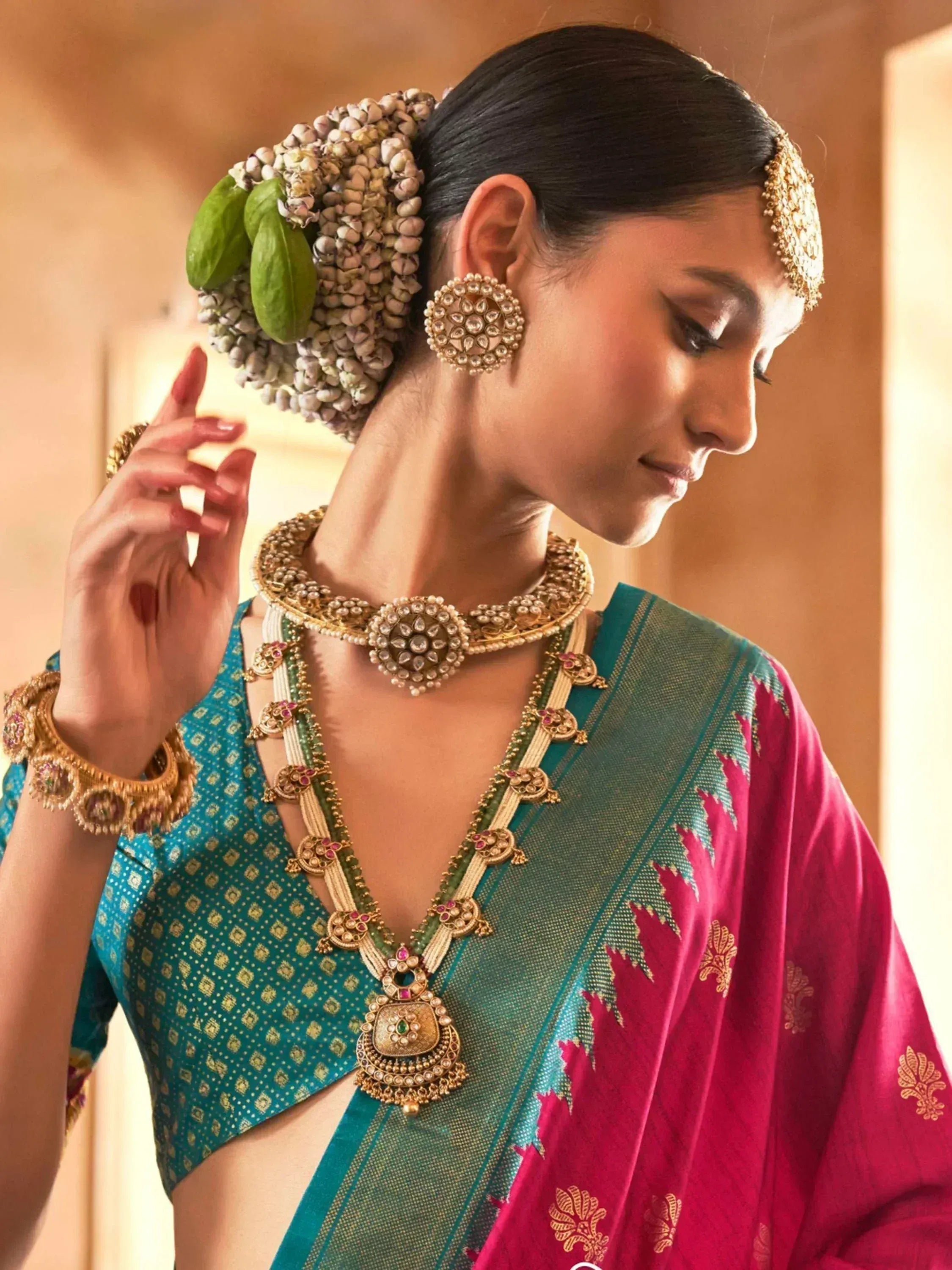 Woman in traditional Indian saree with gold jewelry and floral hair accessory